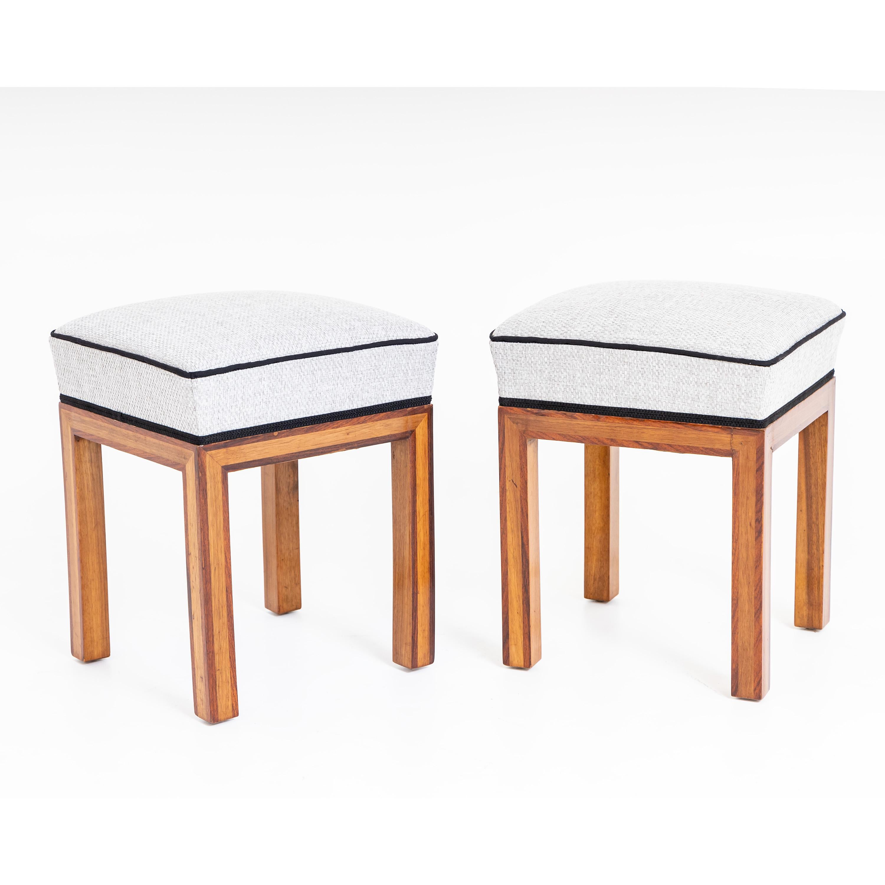 Pair of stools on straight square legs set off with a darker wood. The square upholstered seats were newly covered with a white fabric with black piping and edging.