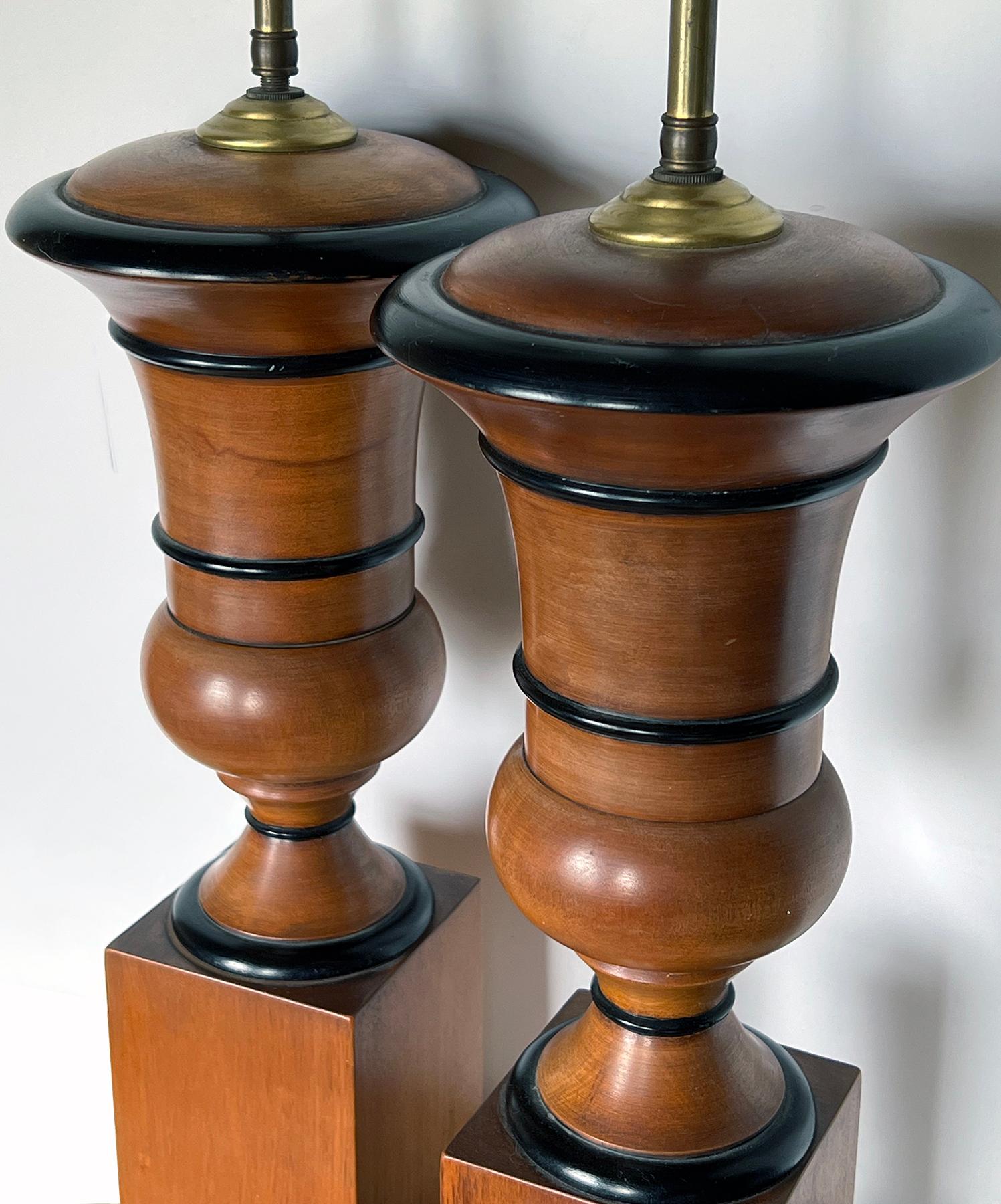each of campagna form with everted lip tapering to a compressed portly body all over a square plinth; adorned with ebonized highlights; 18.5