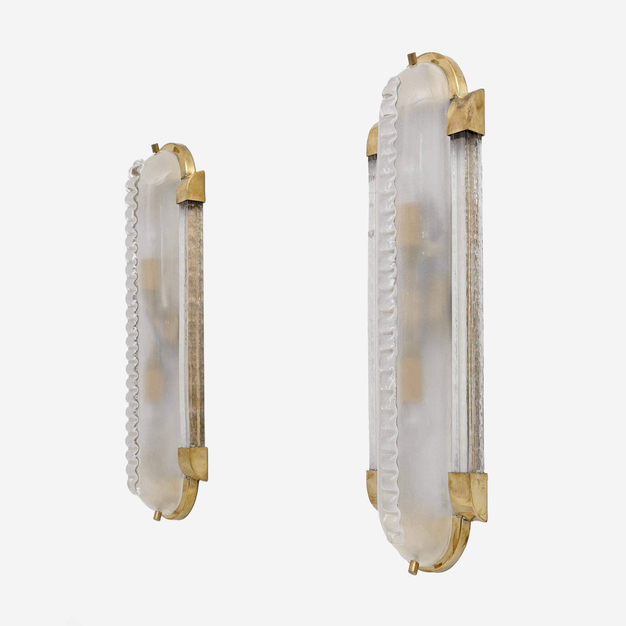Lampade da parete molto grandi, in stile Art Déco in vetro di Murano satinato con lavorazione Morise sulla parte anteriore, montate su una struttura in ottone e vetro, come mostrato nella foto.
Vengono fornite con due prese per lampadine E14 o E12