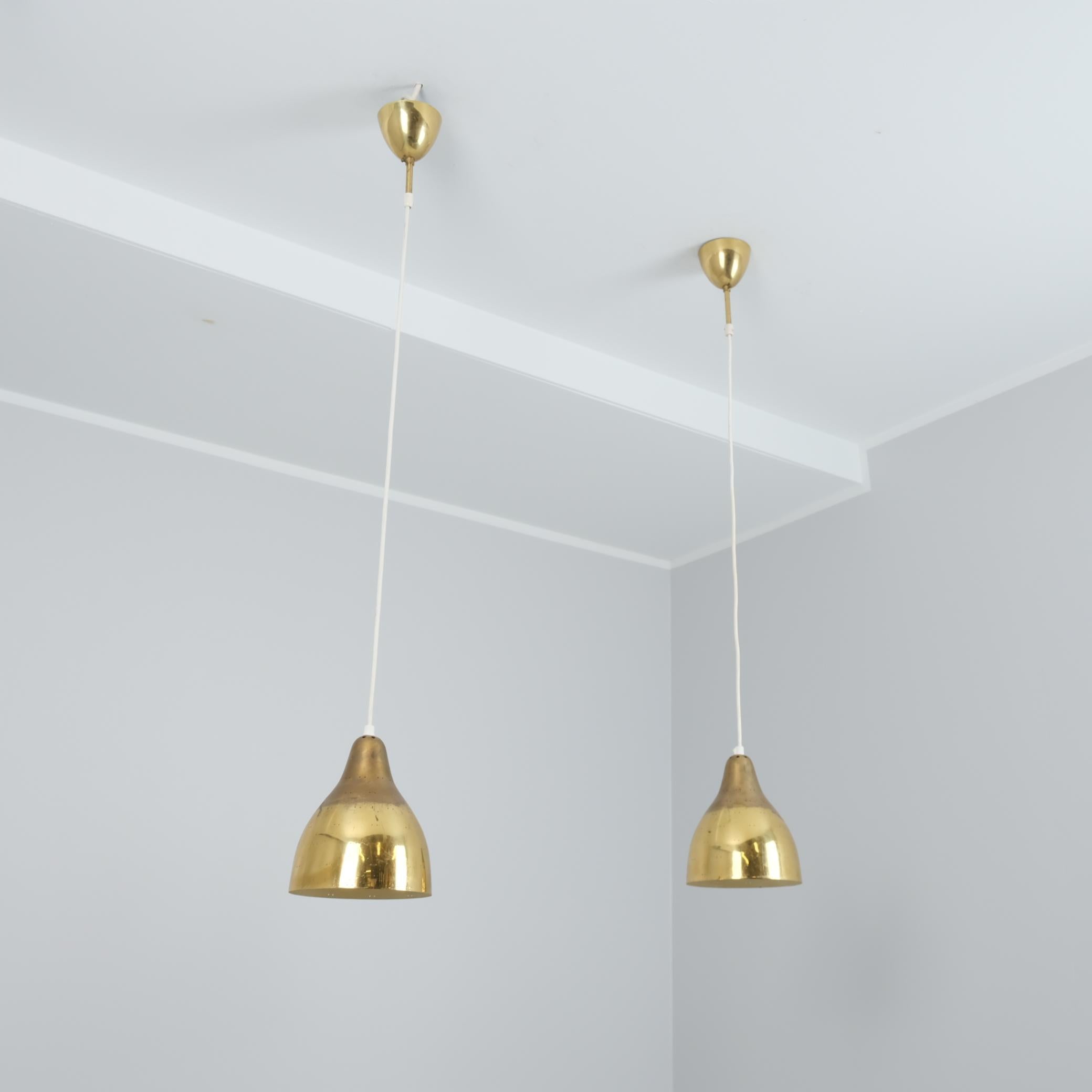A beautiful pair of ceiling pendant lamps in full brass, made by Itsu in Finland in the 1950s. Model ER 84. 

The bell shaped brass shades are perforated with a two-dot pattern, are very beautiful and with their original patina. The lamps are small