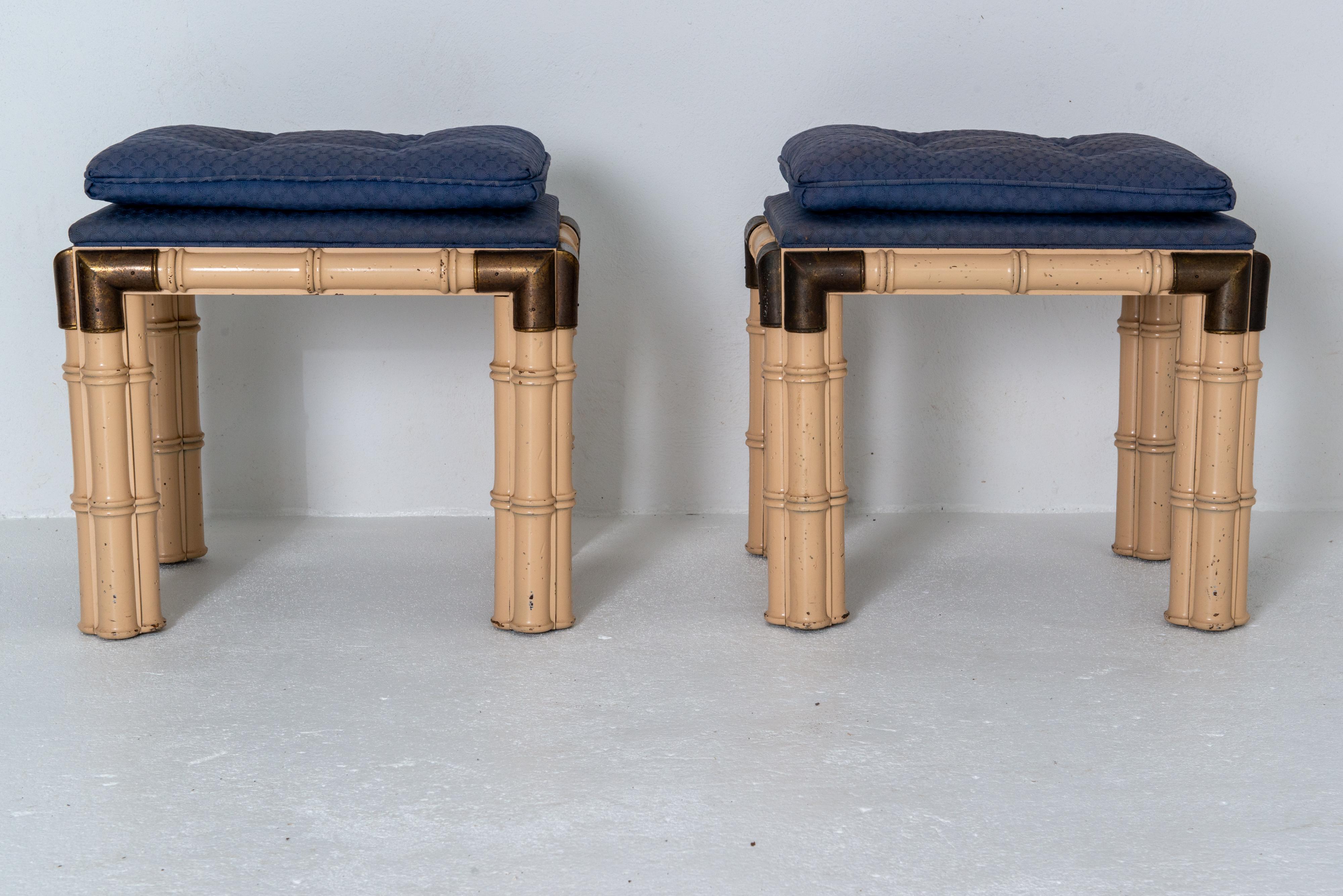 A pair of stylish mid-century modern faux bamboo and upholstered benches in the style of Billy Baldwin. Each wooden leg is carved to appear as a cluster of four bamboo stalks with brass corner pieces. Upholstered tops are a knife edge buttoned tight