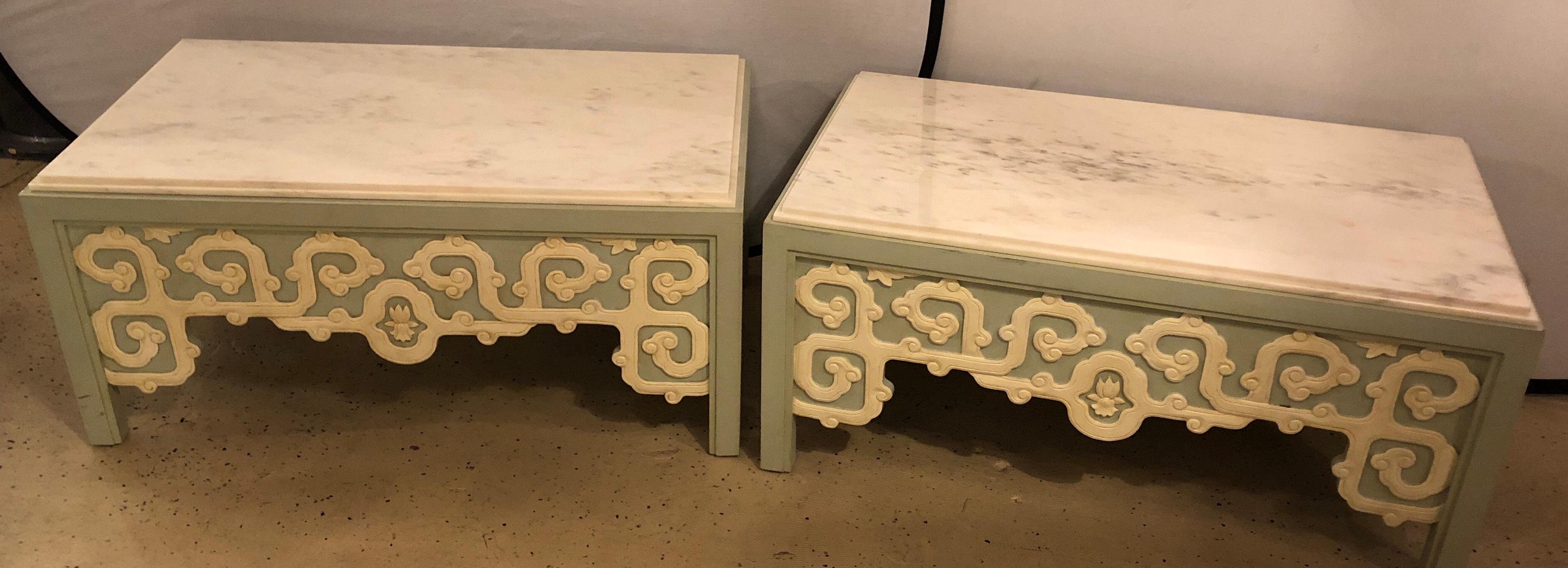 Pair of Billy Baldwin style coffee tables in the Hollywood Regency style having white and grey veined marble tops. The pair of high custom quality form with a green lime base and white painted and carved designs on all sides. Should the white marble