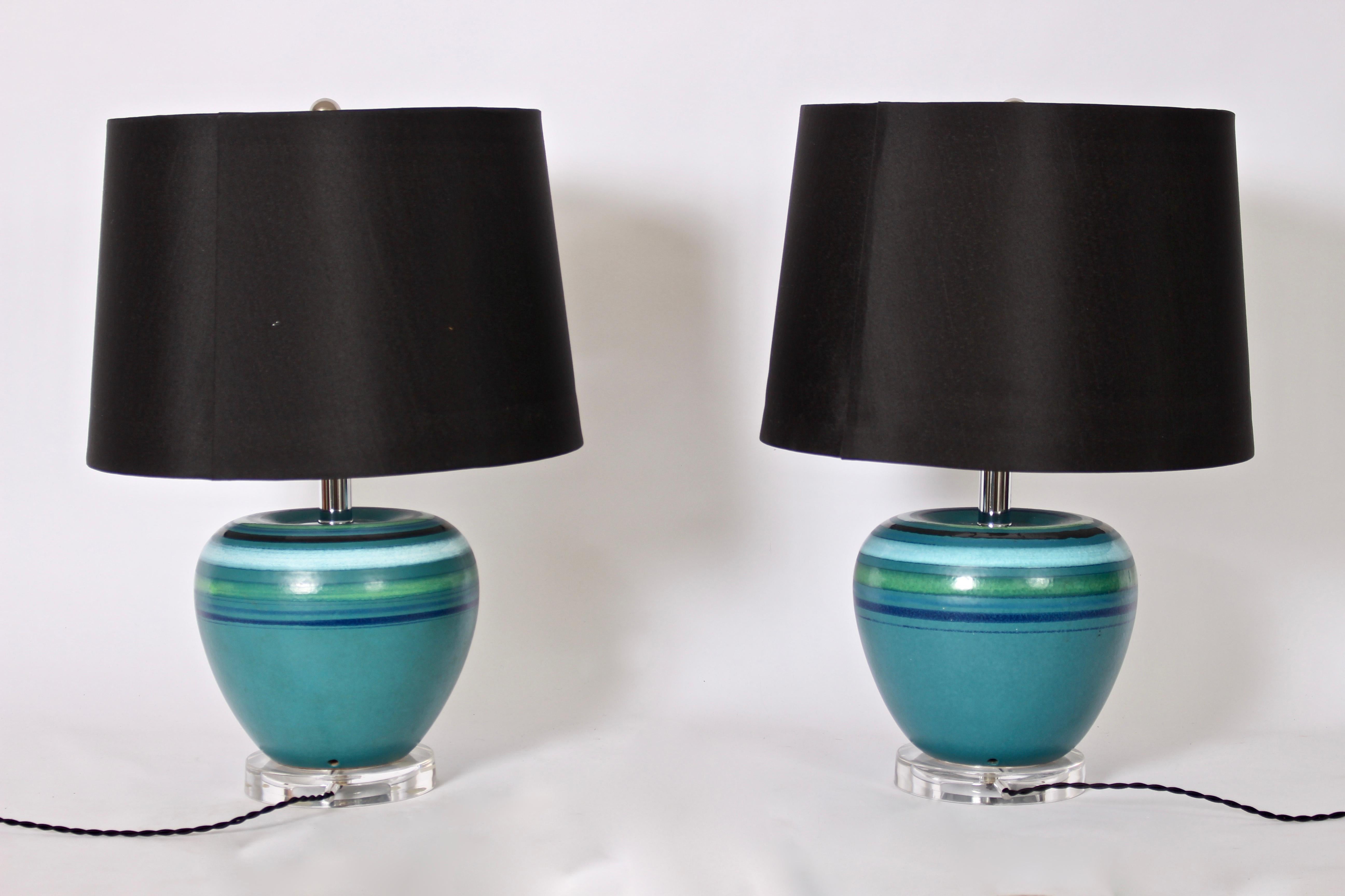 Italian Modern Bitossi attributed Rosenthal Netter blue colored striped bedside lamps, c. 1970. Featuring blue turquoise coloration with horizontal stripes in navy, green, aqua and black on round clear Lucite bases. Black Shades shown for display