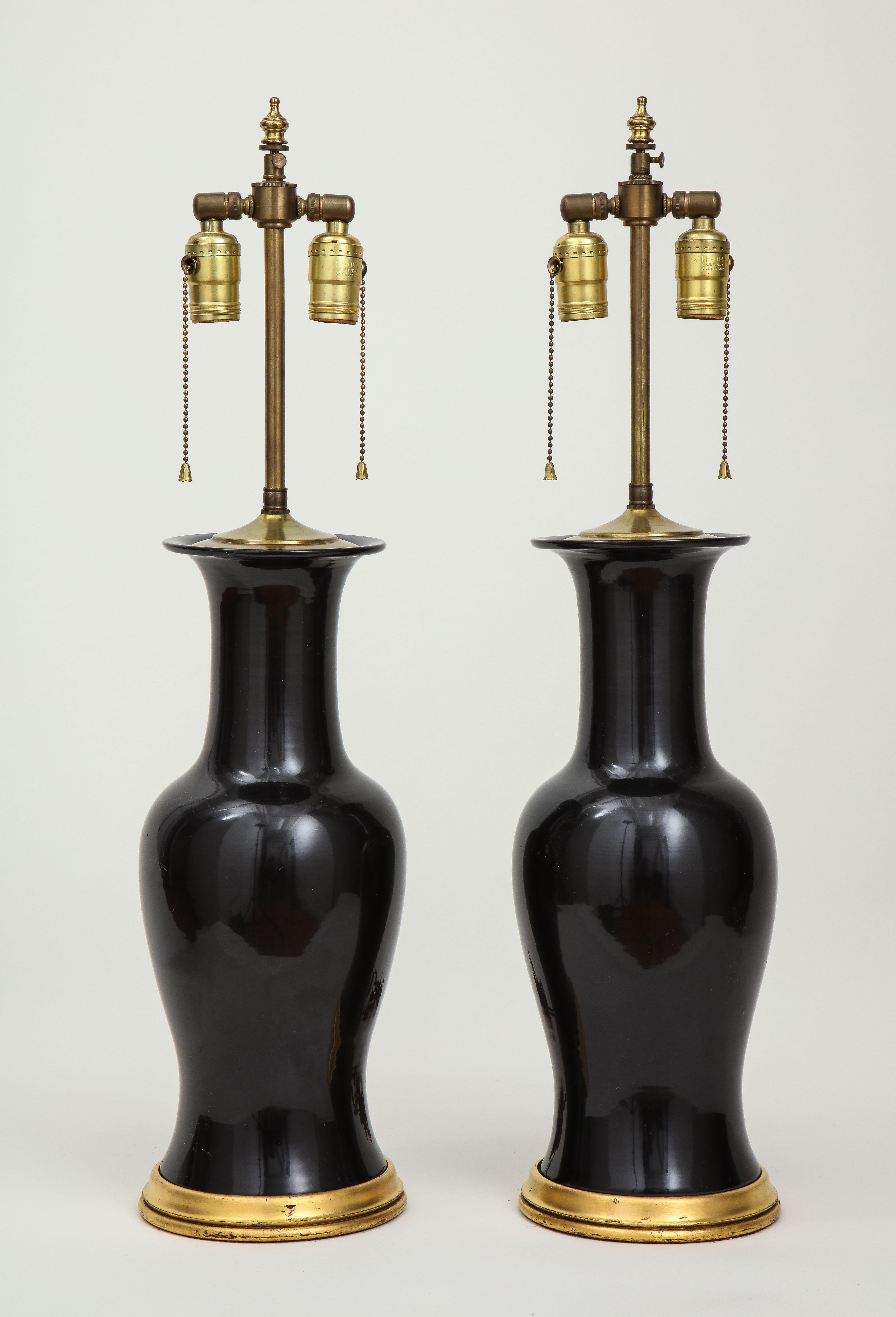 Each fitted with two brass light sockets and adjustable rod to change overall height, mounted on a gilt base.