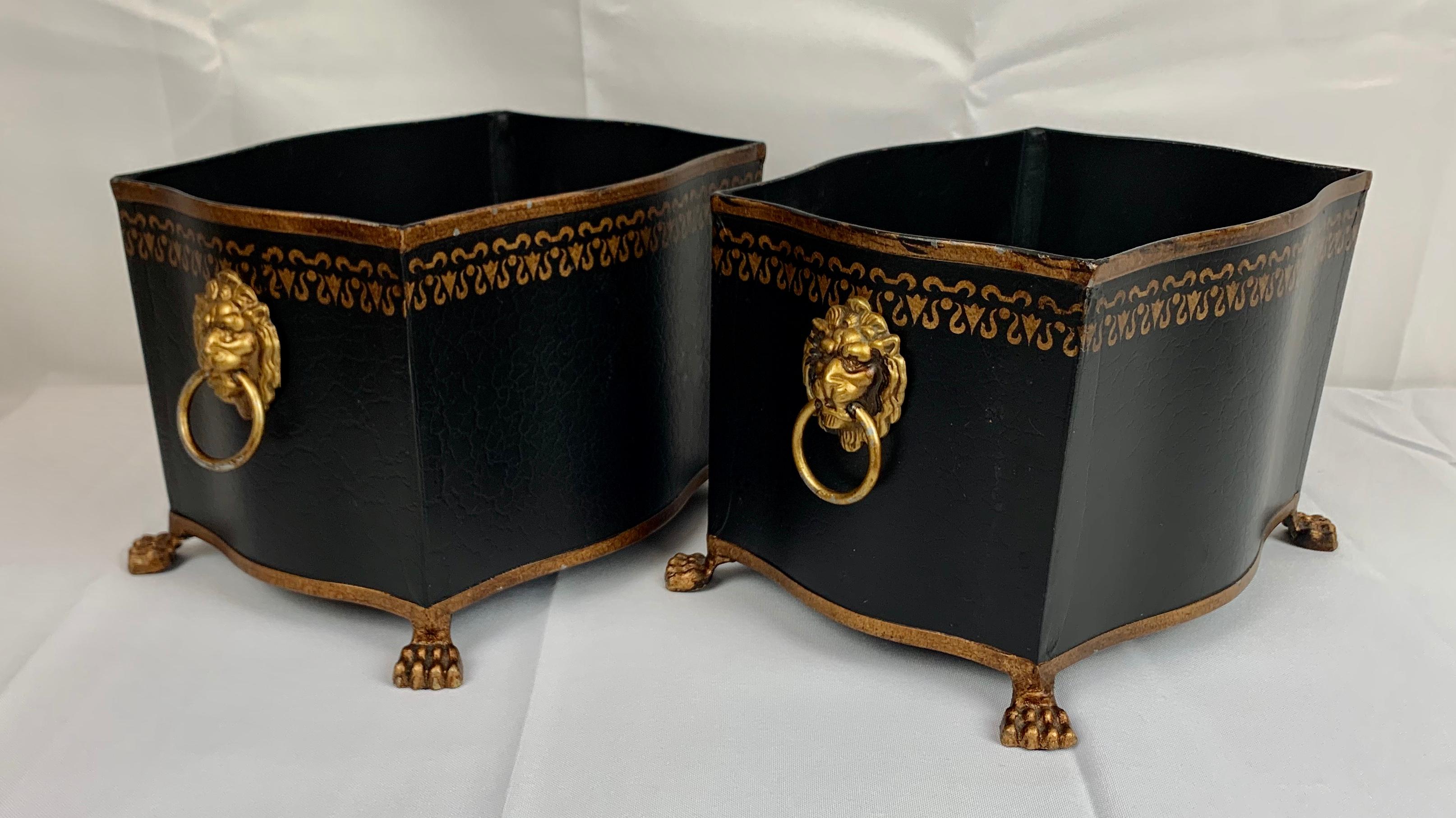 Pair of vintage black and gold cachepots. The cachepots have gilt tracery along the top and gilt lion motif ring handles and paw feet. They have some wear on the interior, as they were used for plants. They are in good condition.
Measures:
