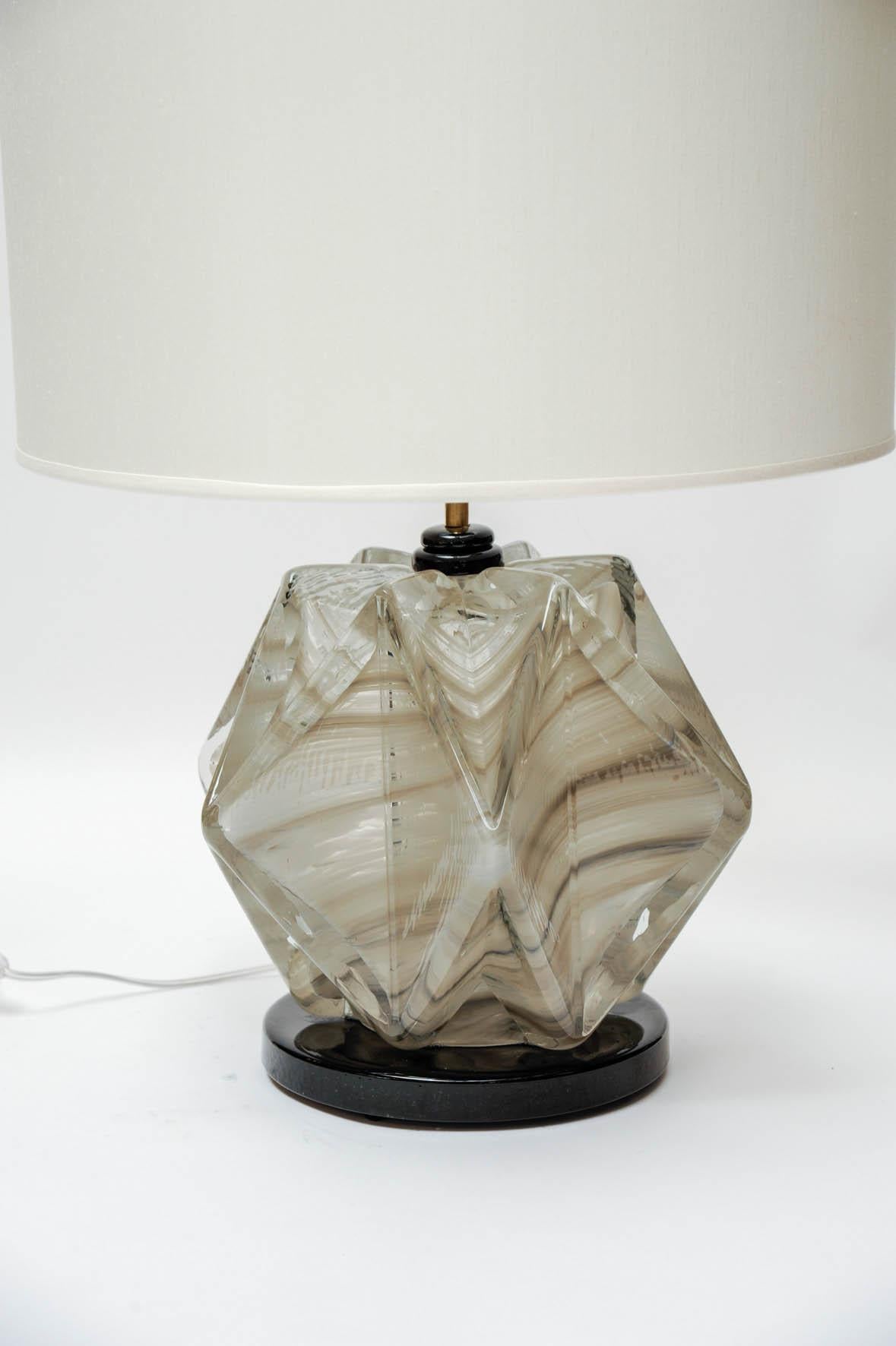 Pair of circular table lamps made of a round black foot and glass body with diamond shapes tinted with hints of grey and brown.