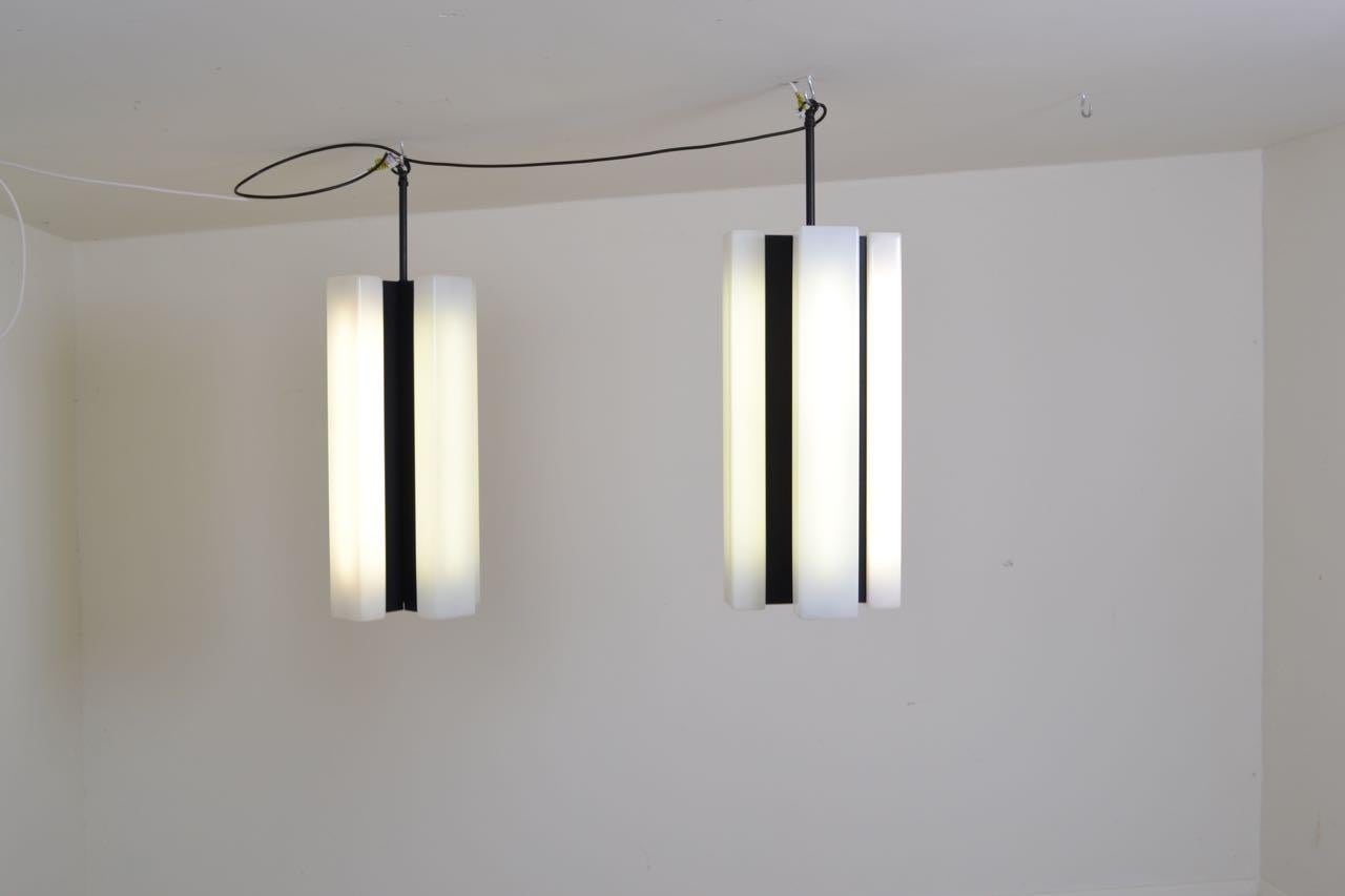 Pair of black lacquered metal pendant lights with opaline acrylic shades. The shades are easily removed to reveal neon tube lights.
The lights were salvaged from a musical conservatoire in Milan, Italy.
 