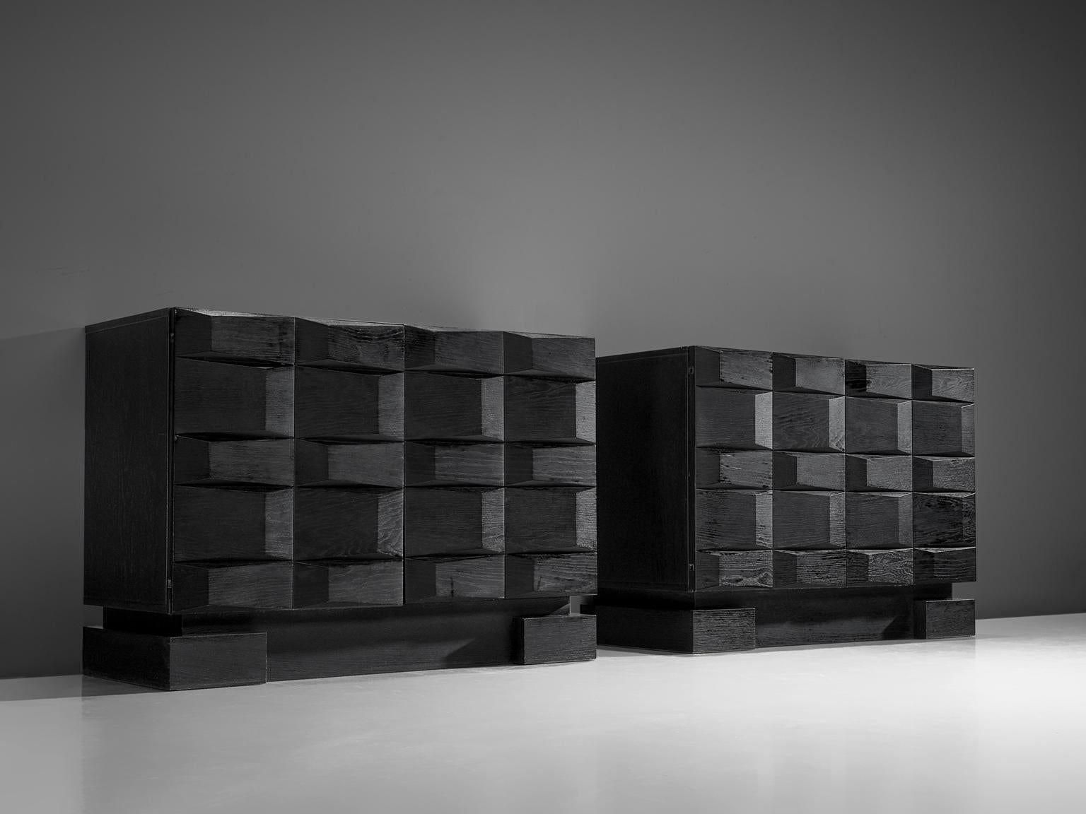 Pair of brutalist credenzas, black wood, Belgium, 1970s. 

Modern and clean pair of two-door sideboards. Two door panels, each with an exceptional three-dimensional pattern executed in black. The continuous pattern gives this bar-cabinet a very