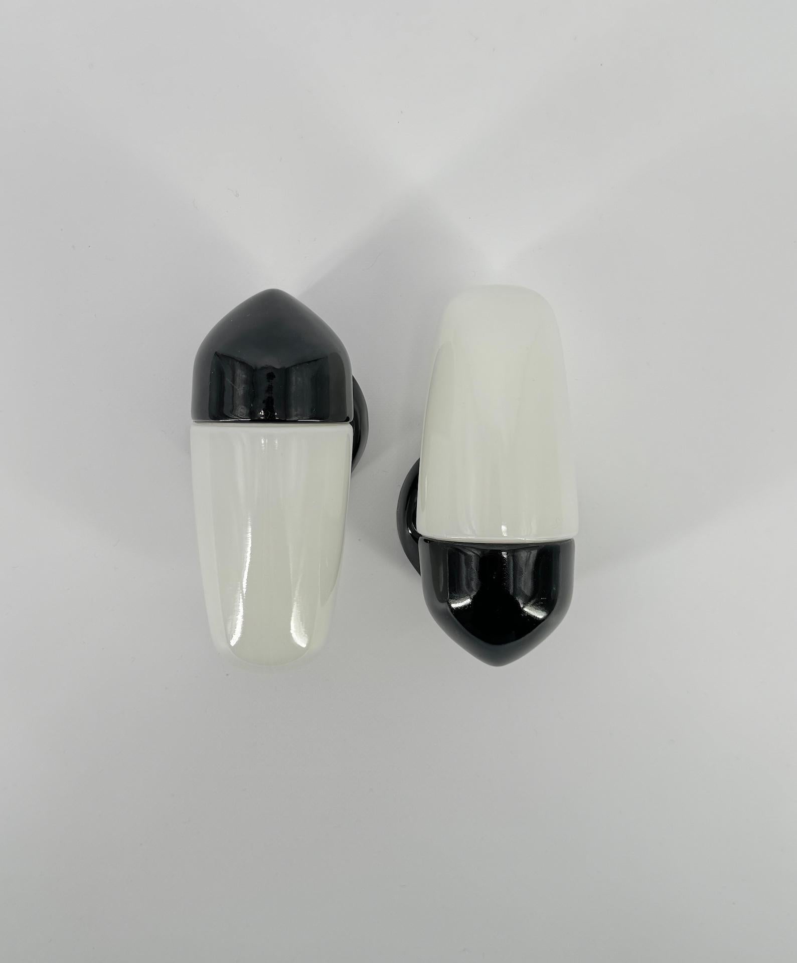 Les appliques en porcelaine noire et les abat-jours en verre opalin ont été conçus par le designer allemand Wilhelm Wagenfeld, qui a étudié à l'école du Bauhaus. 

Ce modèle date de 1958 et présente des lignes épurées, rondes et élégantes, un design