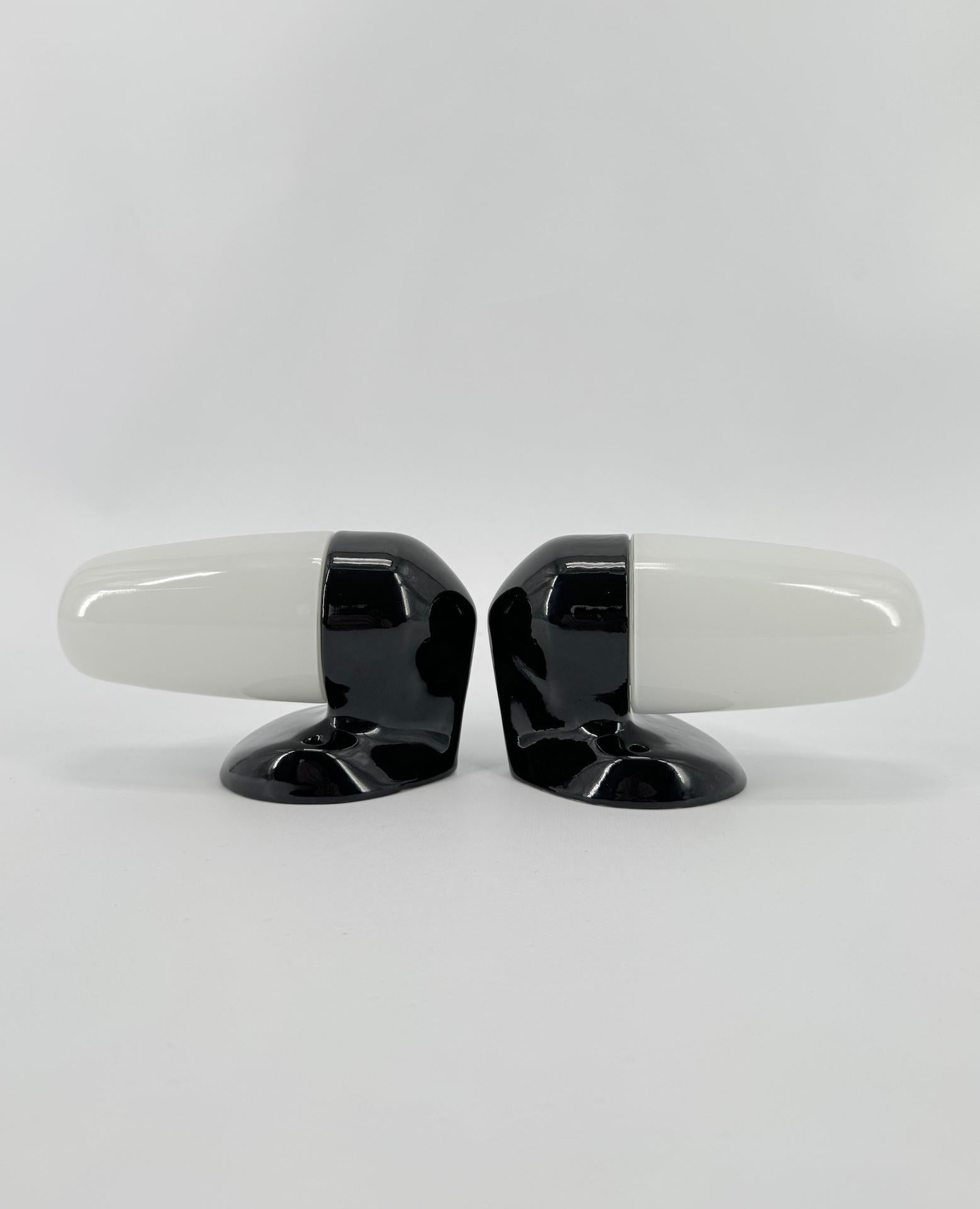 Wall light in black porcelain and opaline glass shades designed by the German designer Wilhelm Wagenfeld, who studied at the Bauhaus school. 

This model dates from 1958 with sleek, round and elegant lines, a timeless design that will look equally