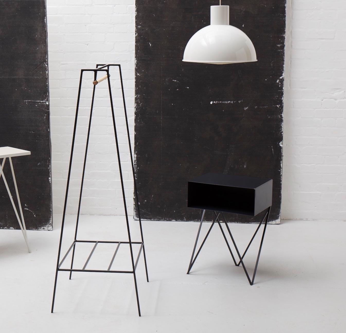 A pair of black Robot bedside tables. The Robot side table features an open shelf on zig zag legs. A fun and functional design made of solid steel, powder coated in a matte black. The clean lines look great against period details as well as in