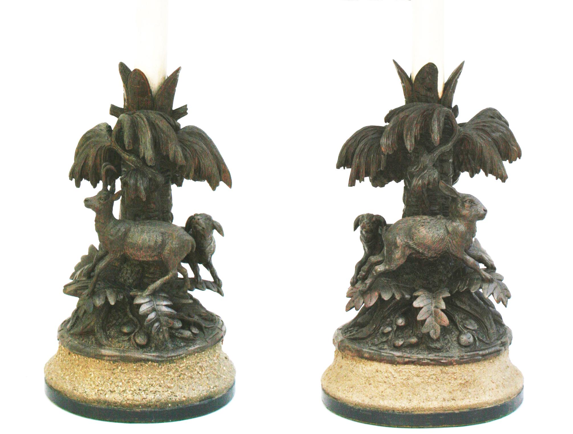 This pair of lamps is done in the unique Black Forest style, carved with a typical hunting theme. A hunting dog chases a hare around one base and chases a deer on the other. Both are decorated with typical maple leaves and acorns. A unique pair of