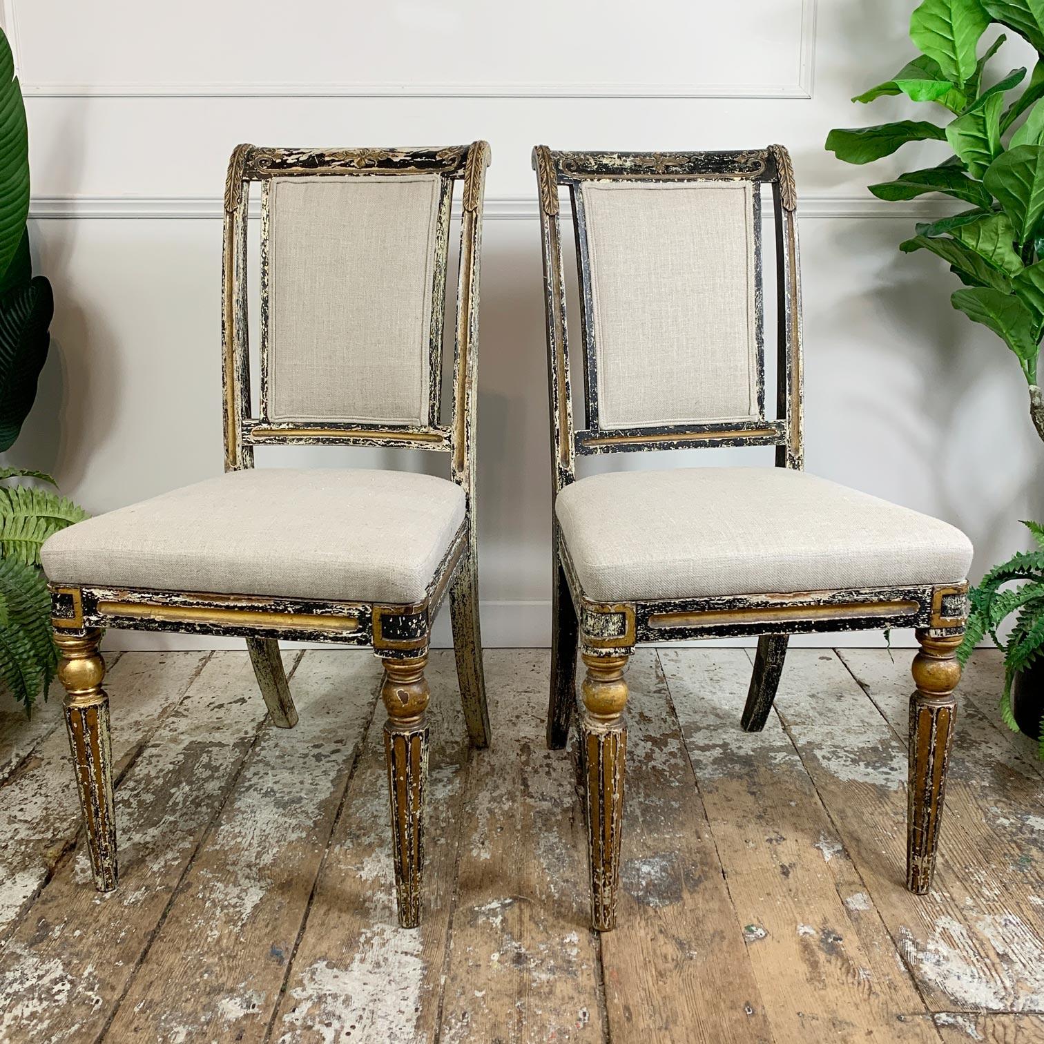 Pair of antique Regency black and gold dining chairs with sweeping curved back and legs. 

Fabulous shaping and curved design, detailed carvings to the back of the chair and gilt paint highlights across the frame and turned legs. 

These unique