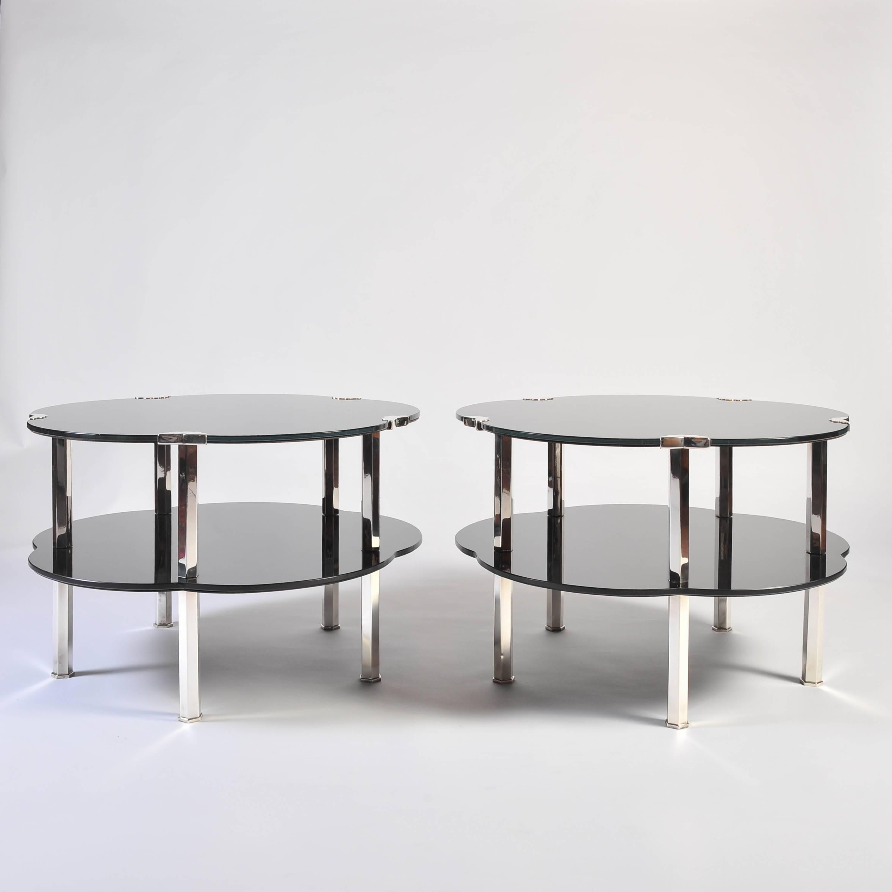 These most glamorous and striking centre, side or coffee tables have two tiers of black glass with silver plated bronze legs and mounts in the French Japonaise manner of the Art Deco period, circa 1927-1933. The five-sided scalloped 