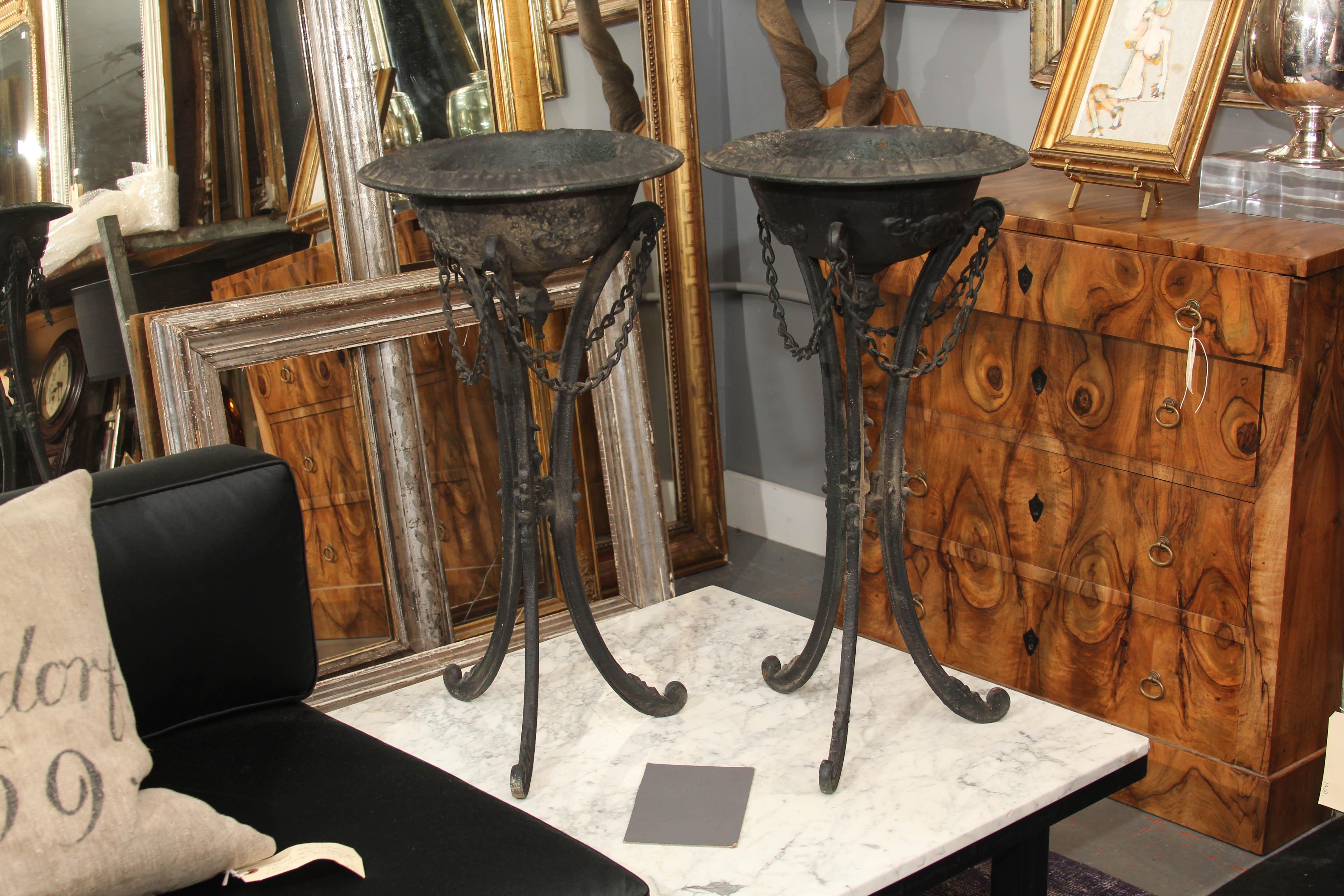 Pair of late 19th or early 20th century iron urns on tall curved tripod legs. These can be outside or used indoors. Beautiful with nothing in them as sculpture, lovely with an orchid or some other plant in them.