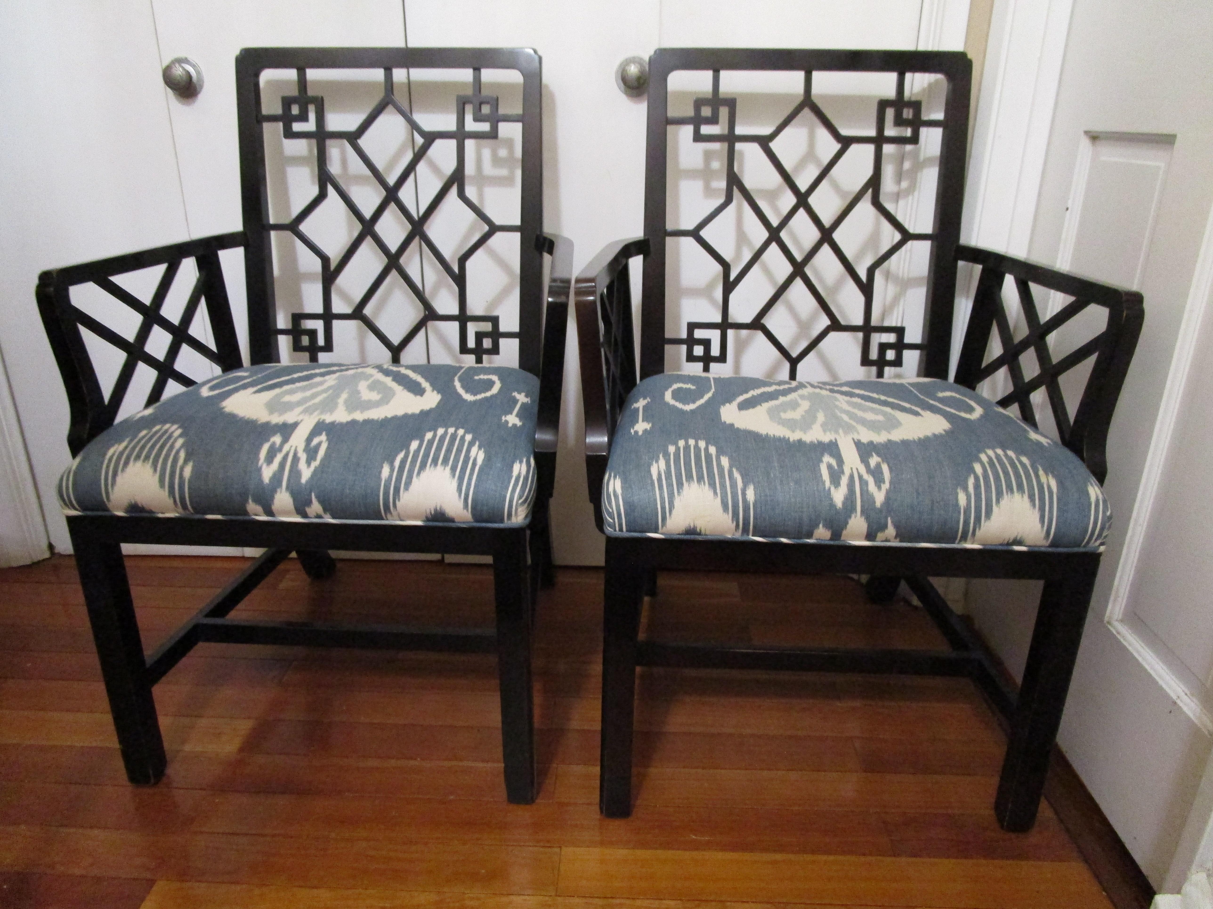 Pair of Baker Stately home black lacquer Chinese style chippendale chairs are stunning. The pair has beautiful blue and white cushions and gorgeous fretwork. The silhouette of the chairs is enhanced by graceful saber legs in the back and straight