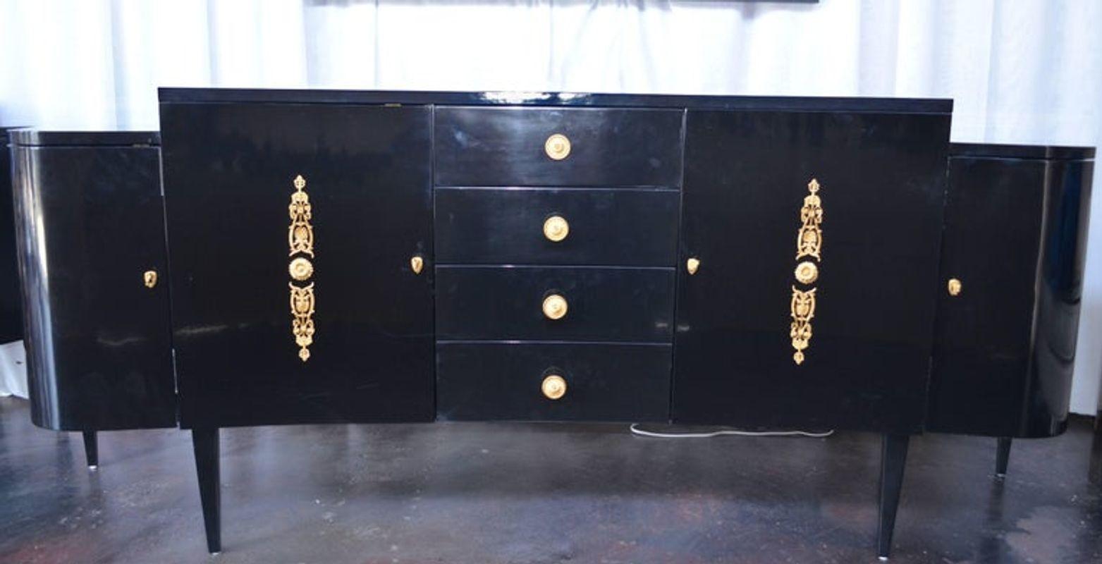 Pair of black lacquer commodes. The commodes have four front drawers with detailed gold finished bronze knobs. As well as four shelved cabinets with gold accents.