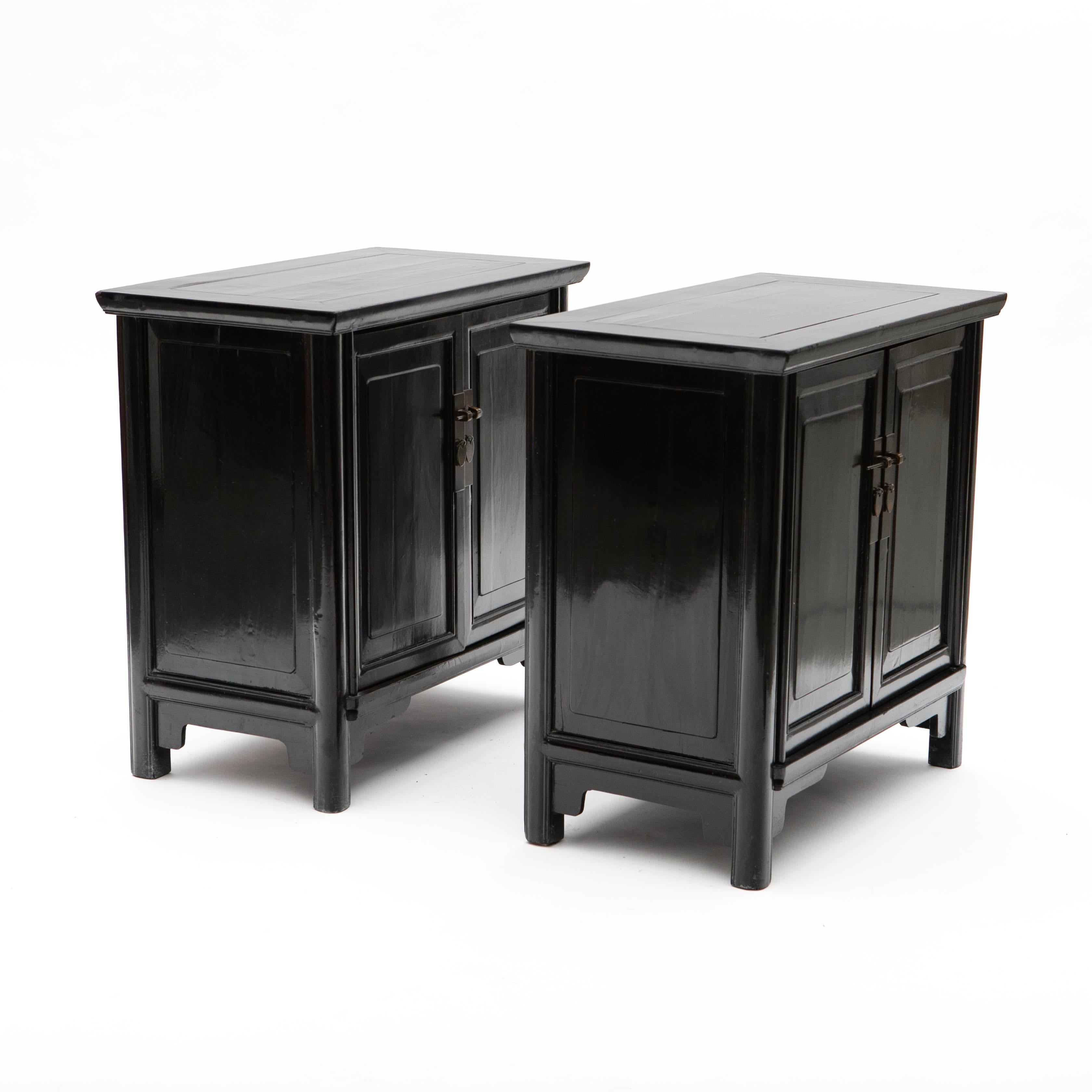 Pair of Black Lacquer Cabinets in Ming Style, Fujian Province, 1880-1900

A pair of elegant black lacquer cabinets featuring paneled doors with patinated brass hardware. Behind the doors are shelves for storage.
The sides of the cabinets are adorned