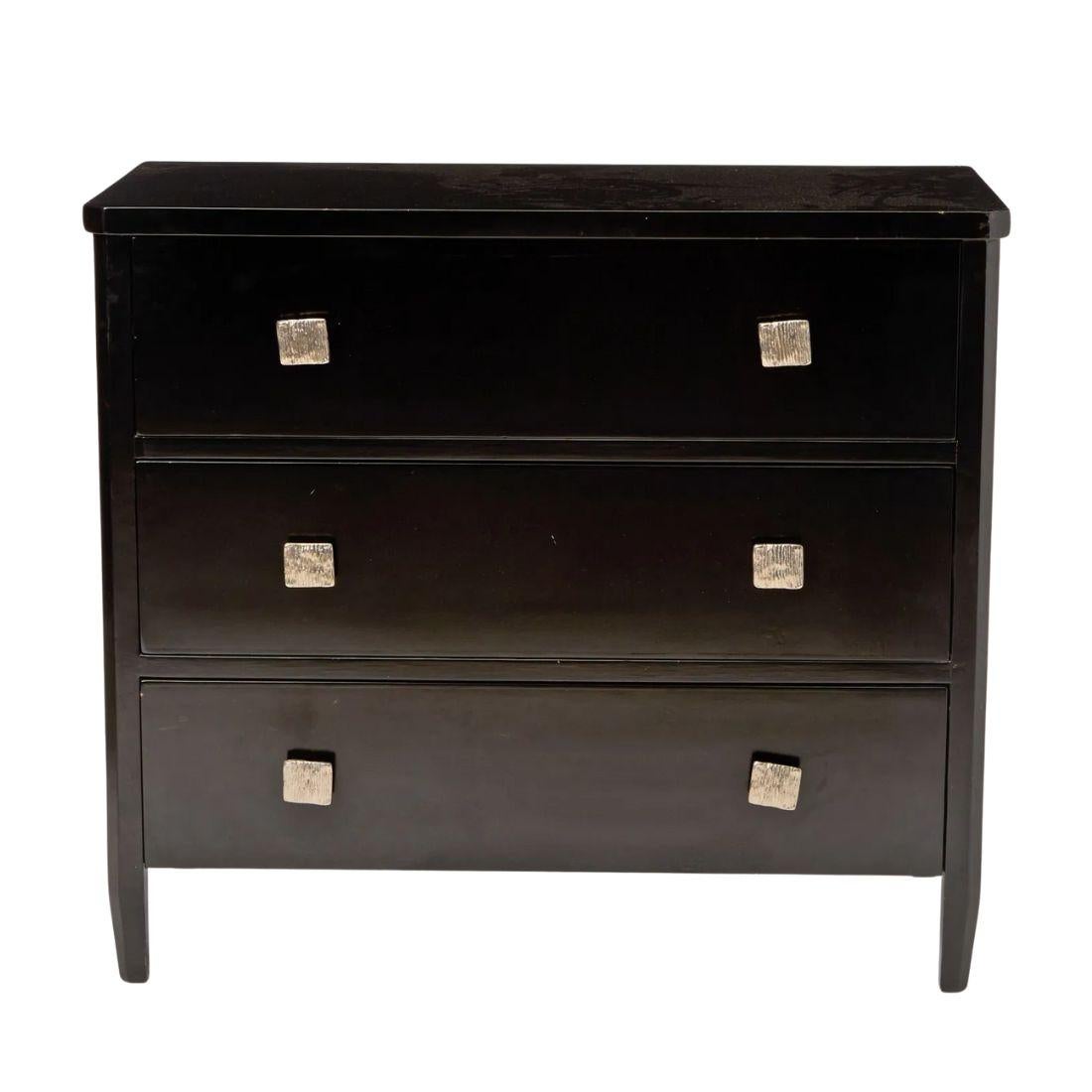 Esta impresionante pareja de cajoneras de estilo Art Decó lacadas en negro ofrece una estética elegante y moderna con un guiño al glamour vintage. Cada cómoda tiene tres cajones espaciosos, cada uno adornado con dos pomos cuadrados plateados que