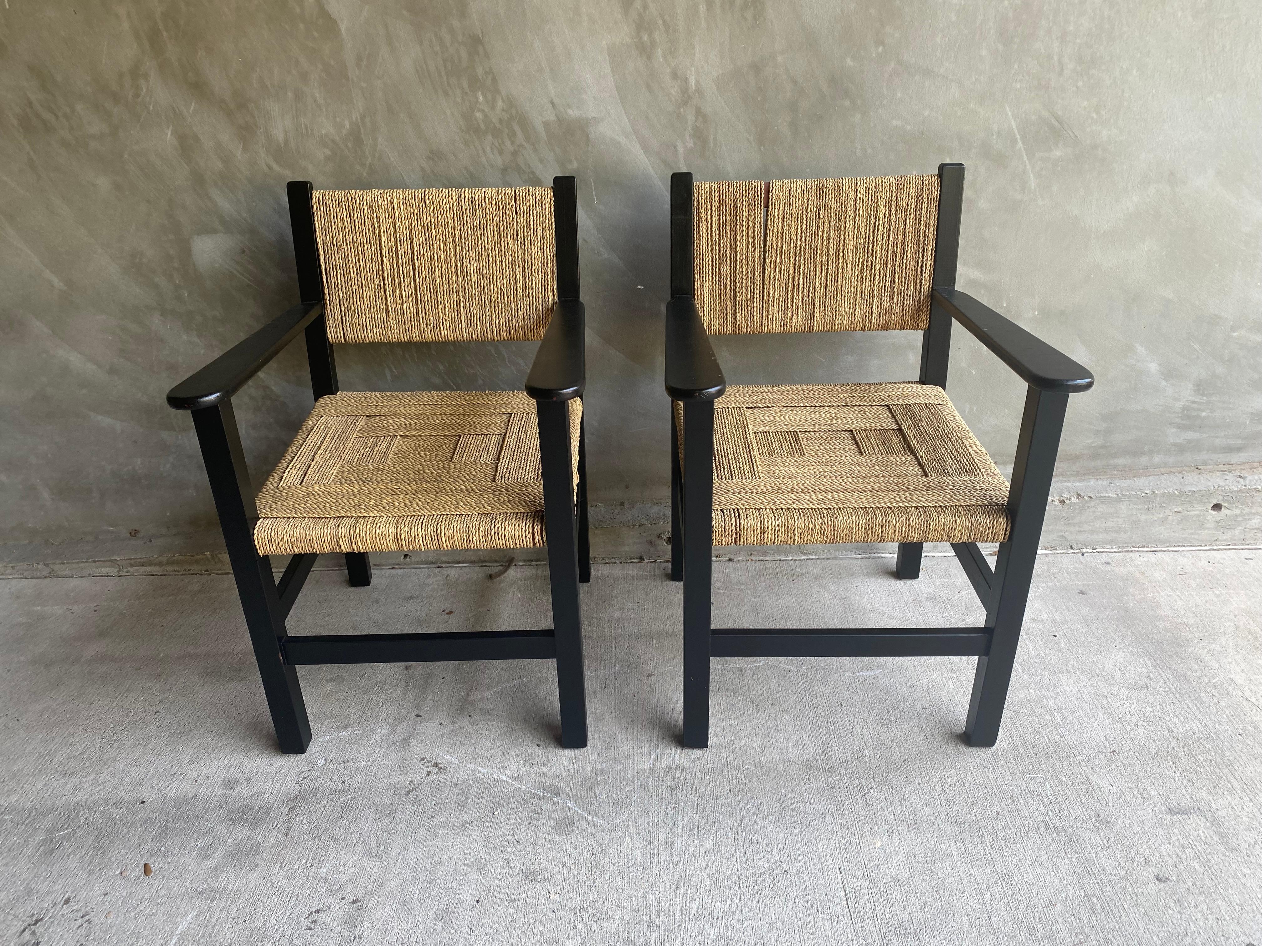 Handsome pair of black lacquered armchairs or side chairs with woven rope seats and backs, in the overall manner of Francis Jourdain and with woven rope in the style of Audoux & Minet. France, 1950's.