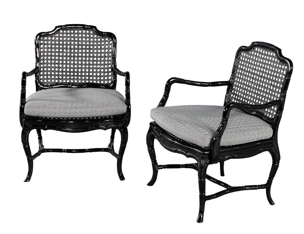 Pair of black lacquered cane back lounge chairs. Unique blend of Chinese Chippendale and Louis the XV styles. Masterfully restored in a high gloss black lacquered finish with newly upholstered thick seat cushion. Fabric is a modern geometric design