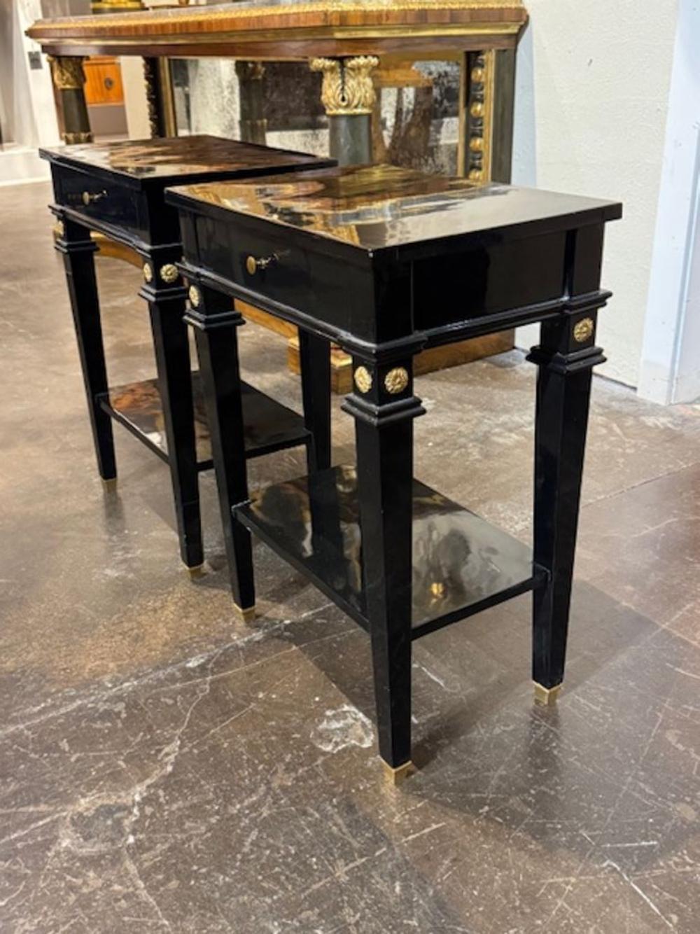 This product is a pair of antique black lacquered Jansen Manner side tables with brass details.  These side tables are stylish and elegant, adding a touch of sophistication to any living space. The classic design adds a sense of history and timeless