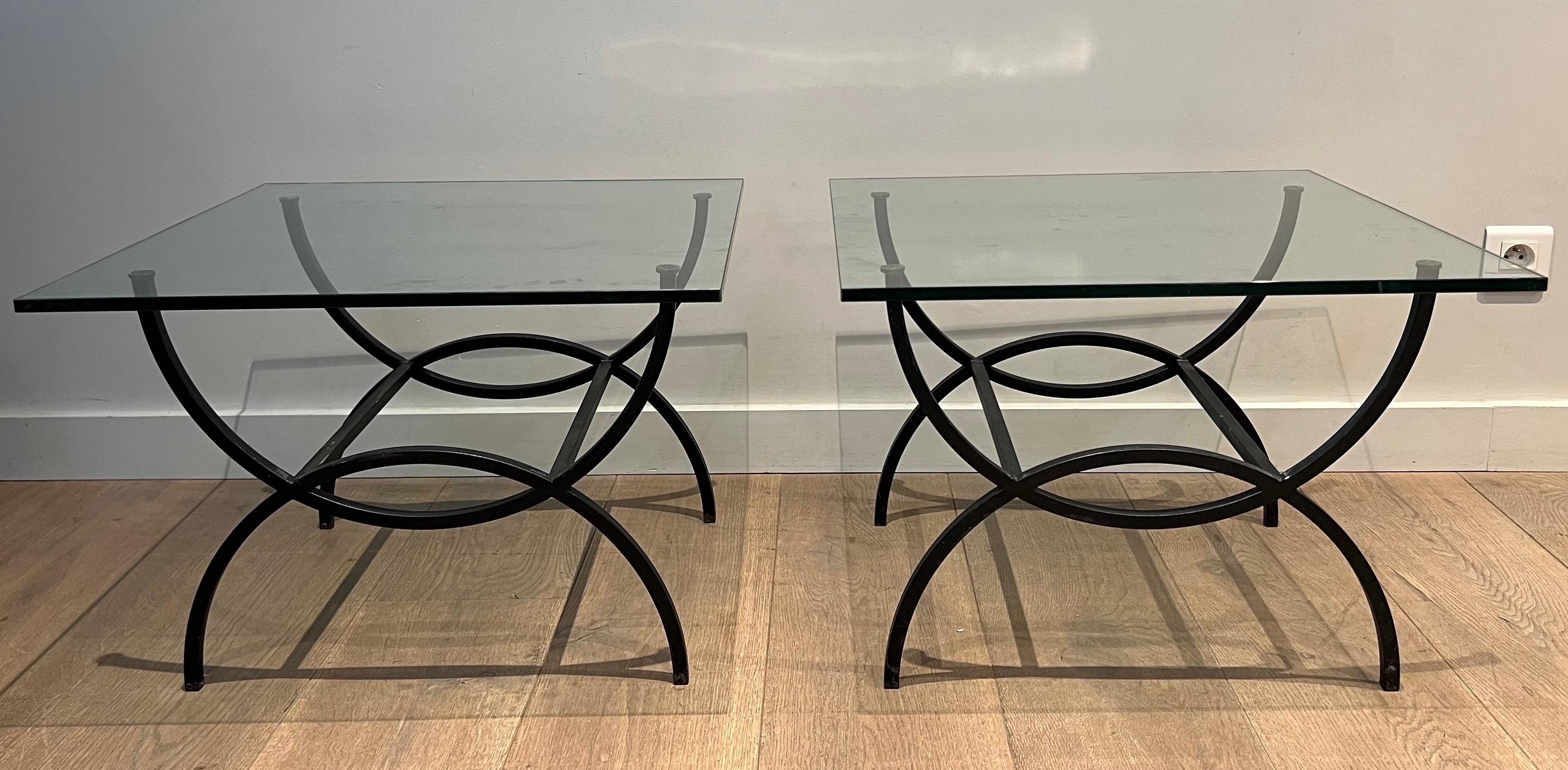 This pair of curule side tables is made of black lacquered metal with thick glass tops. This is a French Work. Circa 1950
