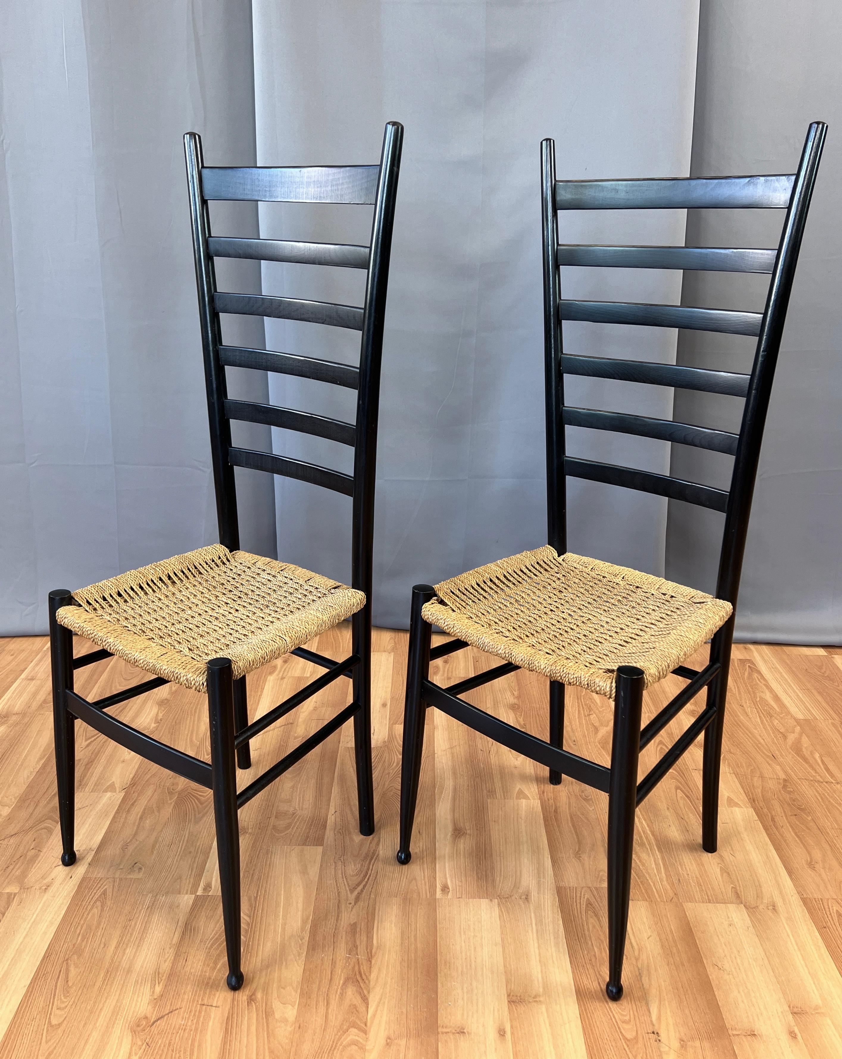 A pair of black ladder back side chairs in the style of the work of Gio Ponti.
Wooden frames, covered in black lacquer, with the seats are a woven rush.