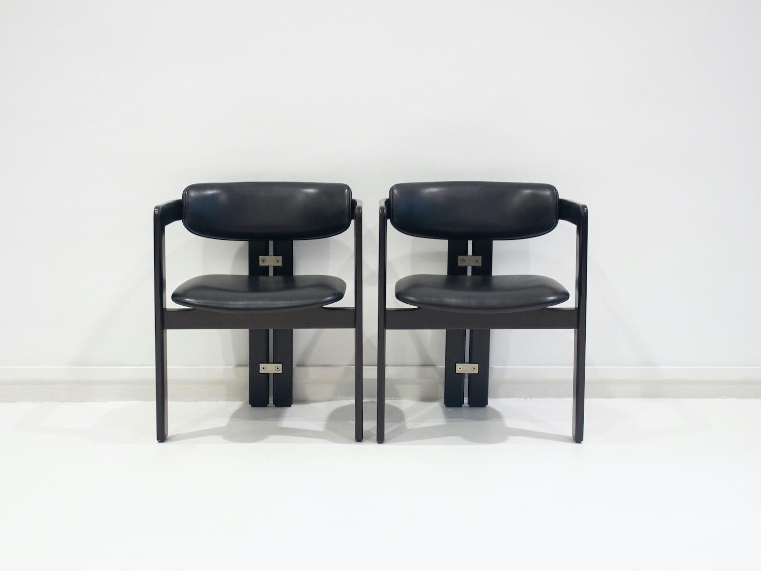 Pair of model 'Pamplona' chairs designed by Augusto Savini for Pozzi in 1965, Italy. The chairs are made of black lacquered wood with a rounded backrest, seat and back upholstered in black leather, rear chair legs braced with aluminum elements.