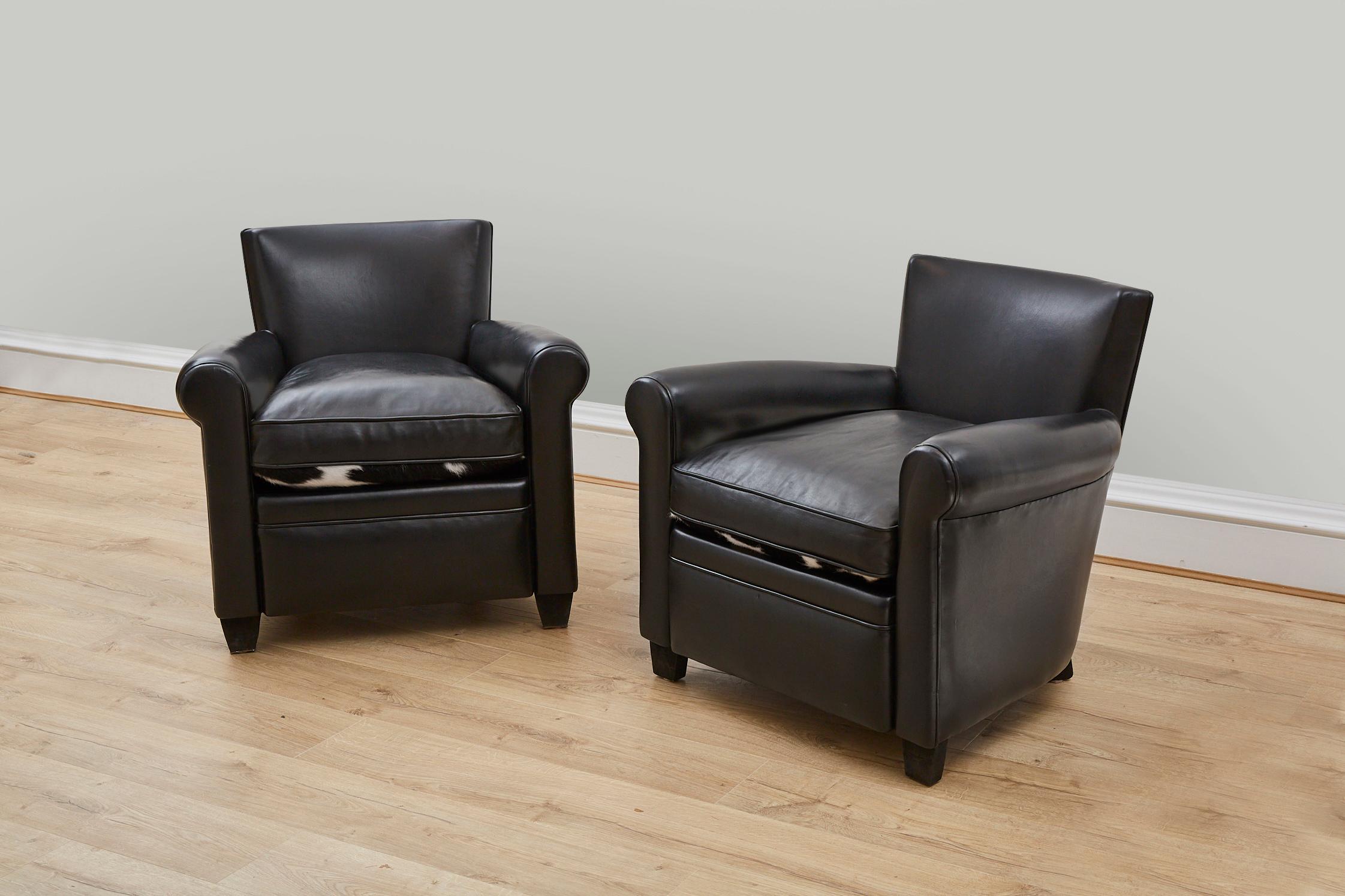 A stylish pair of black leather armchairs featuring reversible seats - black leather on one side with black and white natural cow hide to the other. 

These chairs have been hand made with traditional methods - steel studded detail to the back of