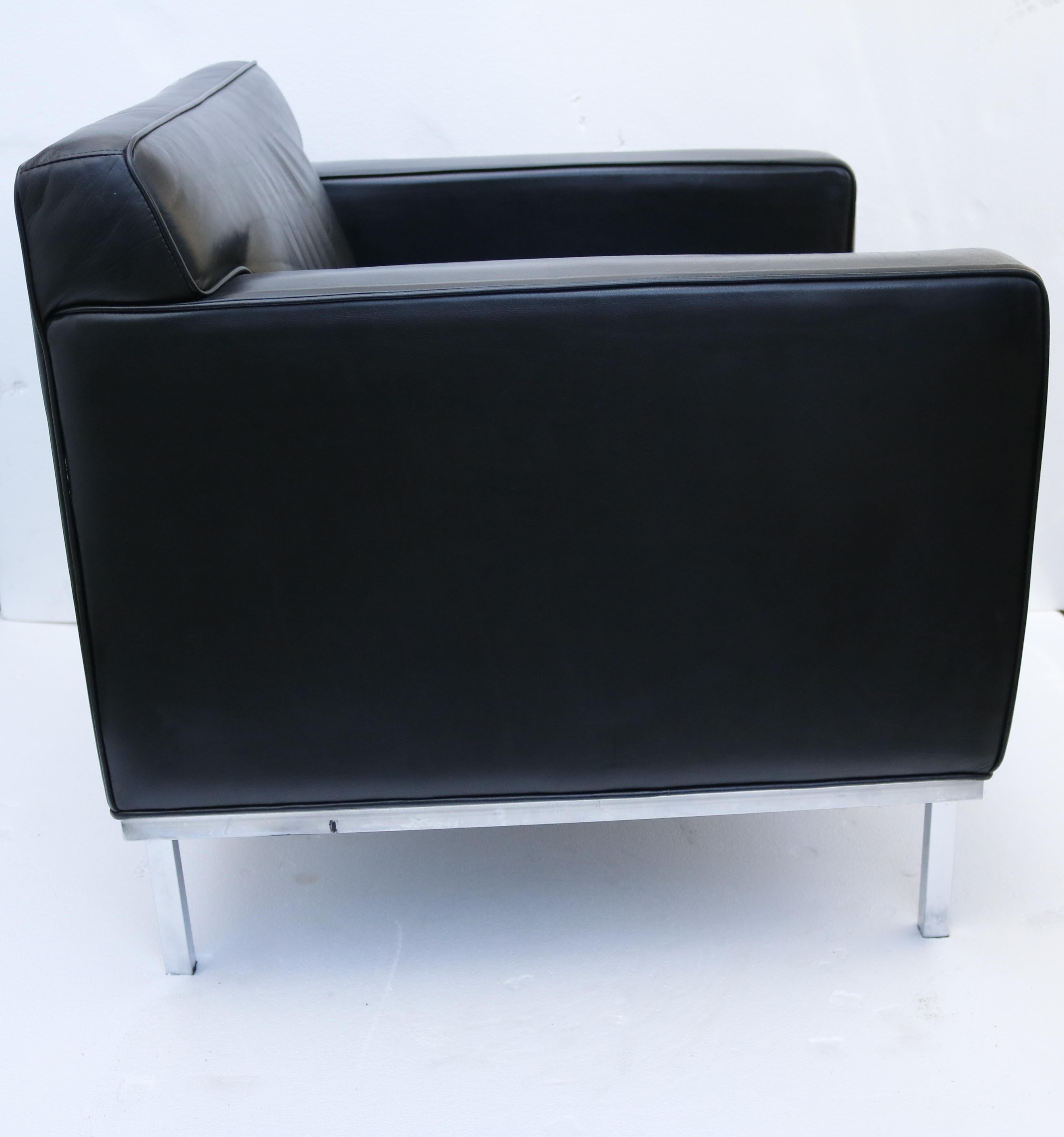 A pair of cubic-shaped club chairs in rich black leather with chrome legs.