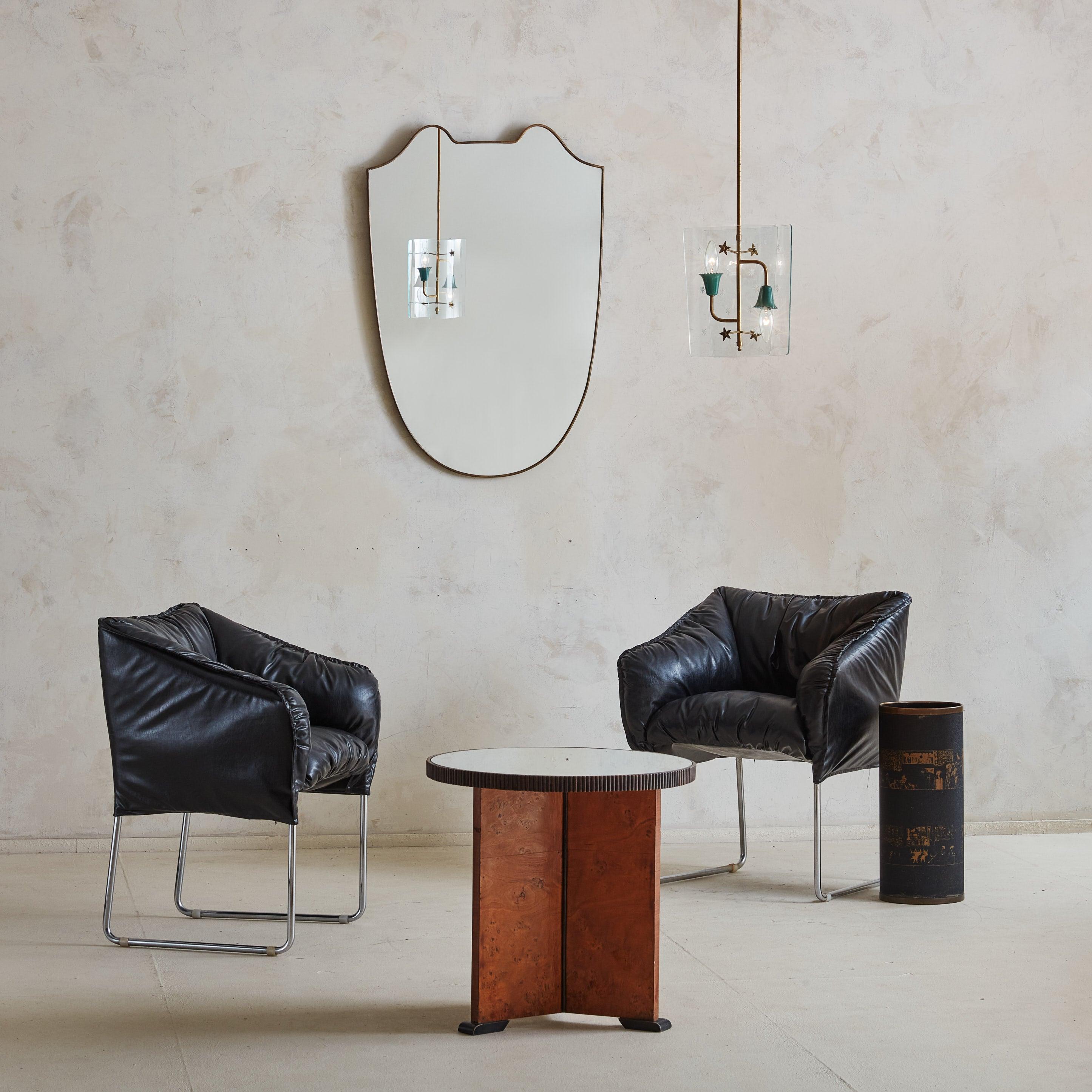 A pair of 1960s Italian Bambole style lounge chairs wrapped in supple black leatherette. The plush, gathered upholstery offers an extremely comfortable, enveloping seat. These chairs feature strong chrome frames, providing support and a striking