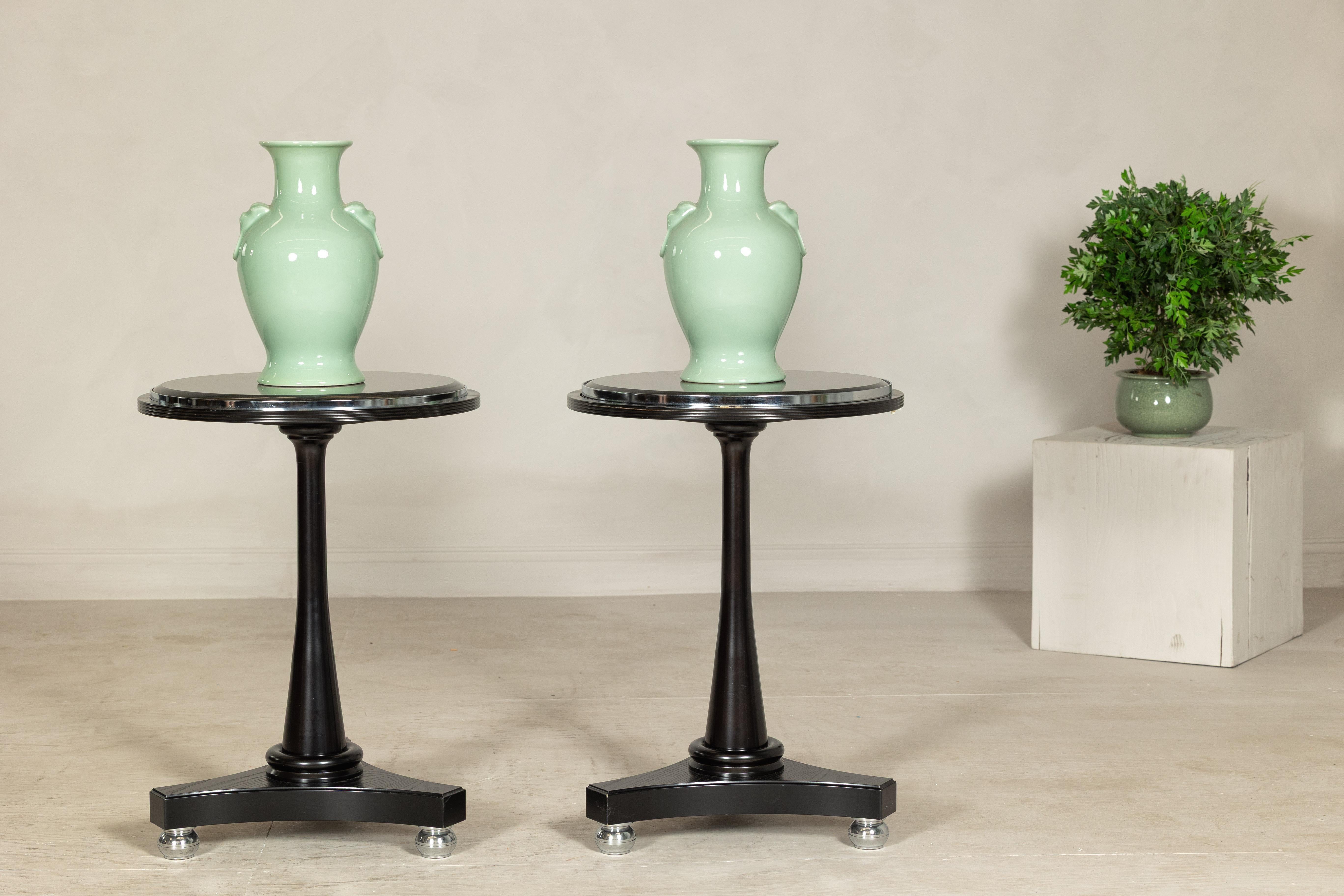 Cette paire de tables de guéridon de la fin du XXe siècle offre une présence audacieuse et sculpturale, parfaite pour les intérieurs contemporains ou les espaces commerciaux haut de gamme. Chaque table présente un plateau rond en marbre noir avec