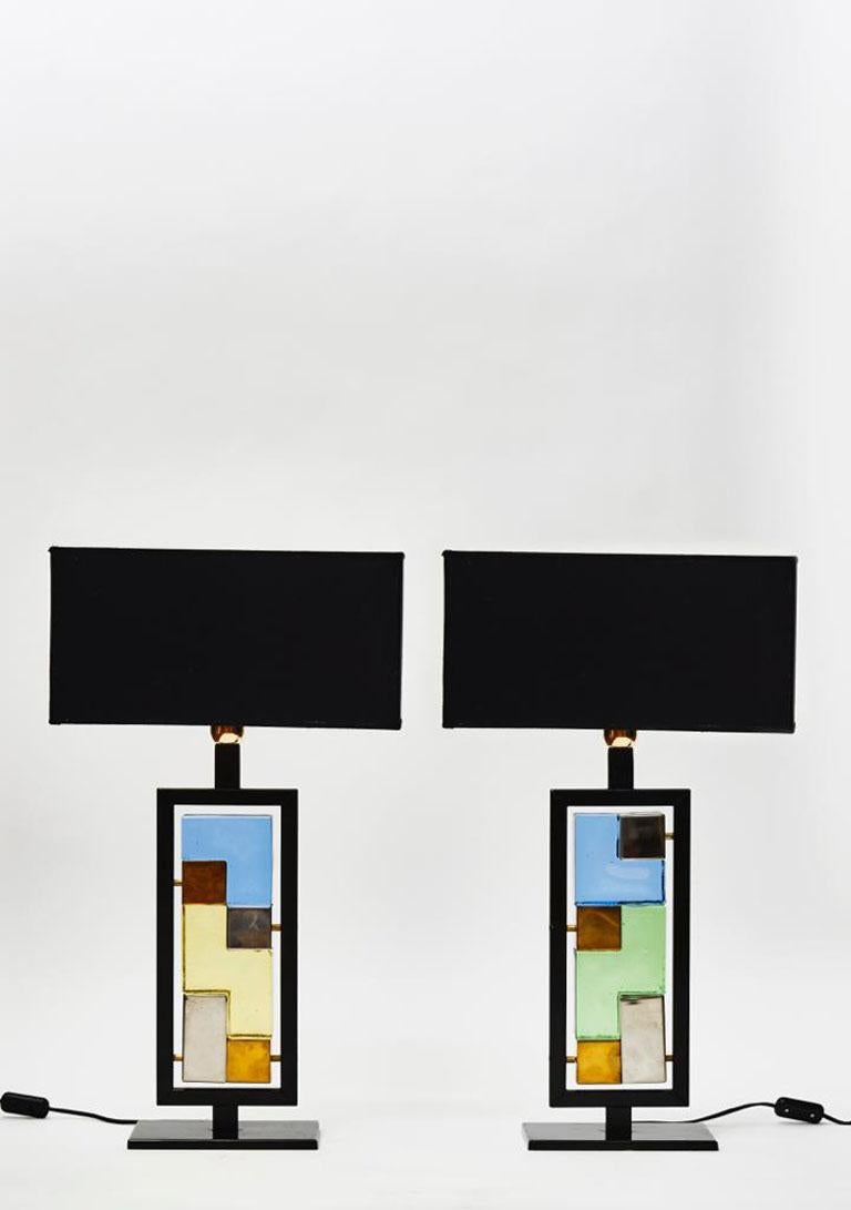 Pair of table lamps made of a painted metal frame circling different bricks of metal and glass.