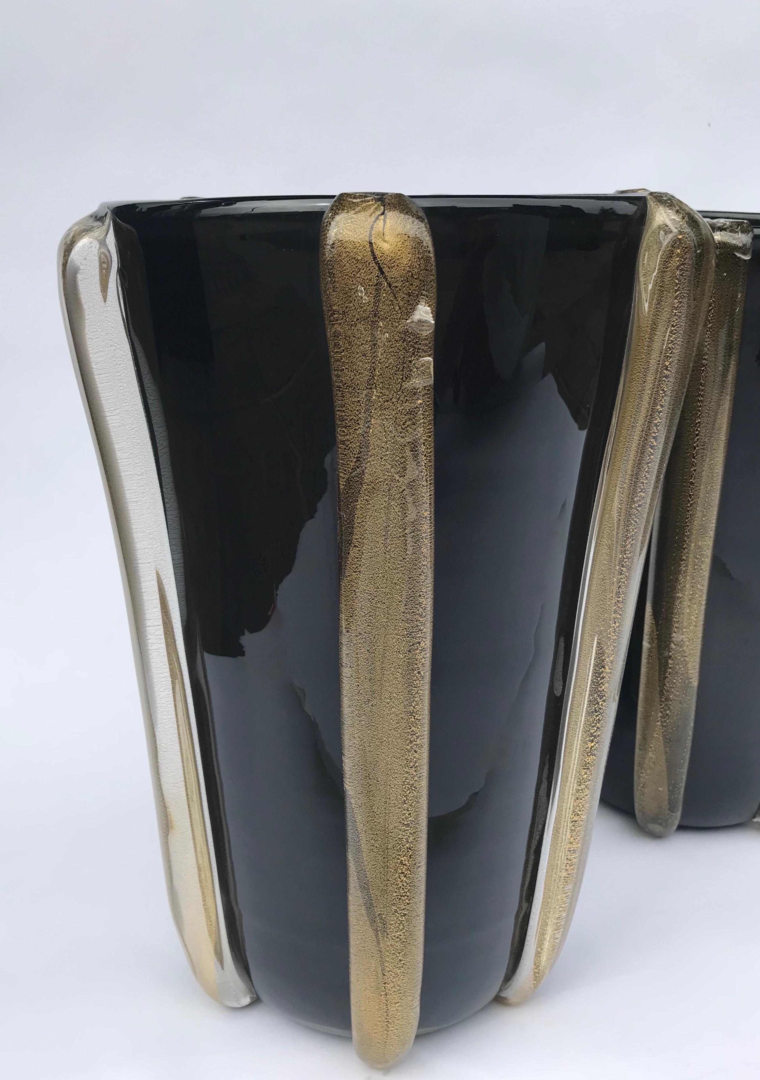 Produced by hand on the island of Murano in Venice, Italy, this pair of black Murano glass vases has clear glass and gold leaf detail. The gold shines through the clear glass giving a beautiful iridescence when the light catches.

Both vases are