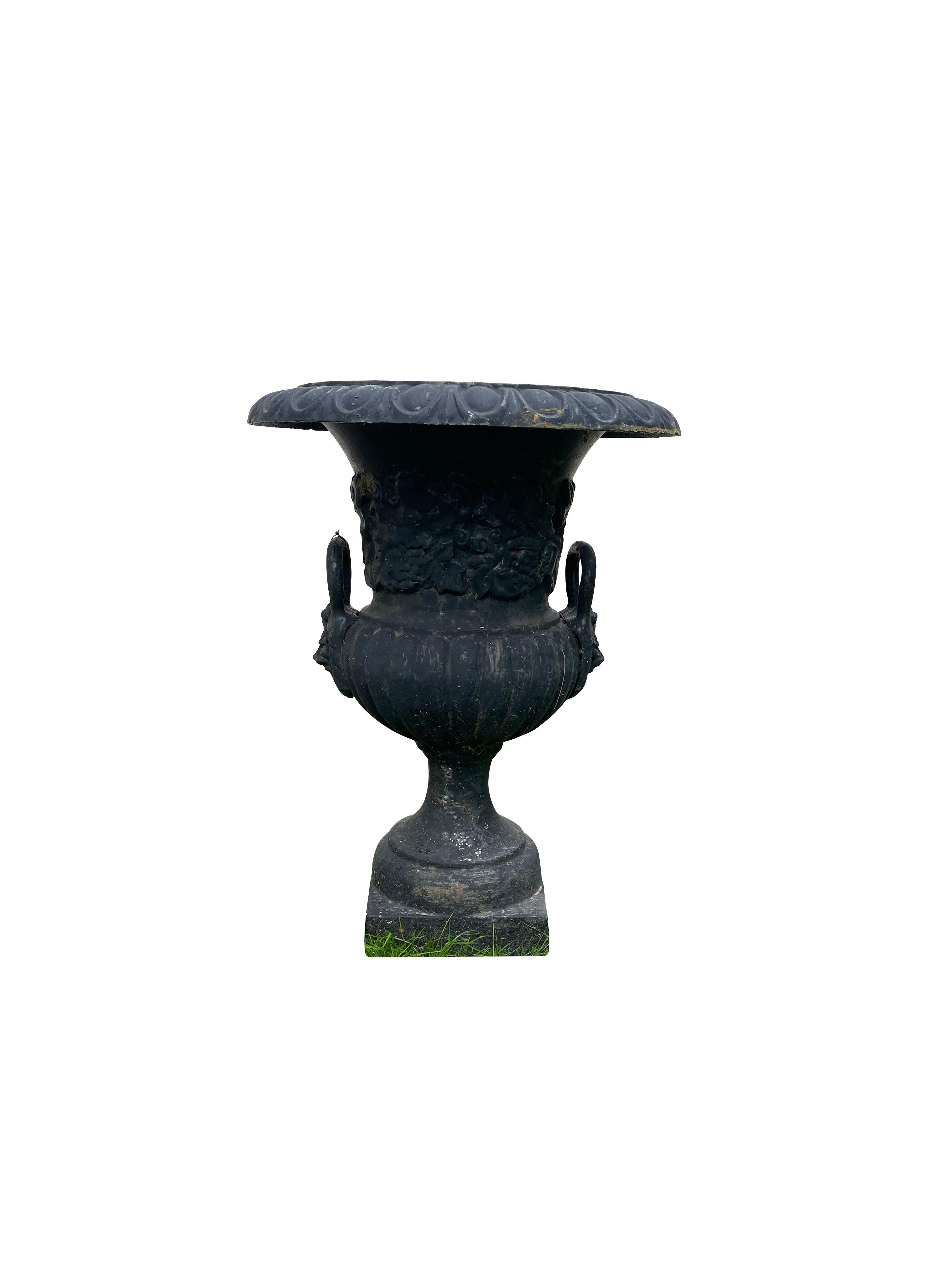 Pair of handled cast iron Campana garden urns, in black. Each one is raised on a -Inch square base with a 6-Inch deep and 14-Inch interior diameter, one drain hole; the rim is decorated with egg and dart ornamentation and the handles are formed with