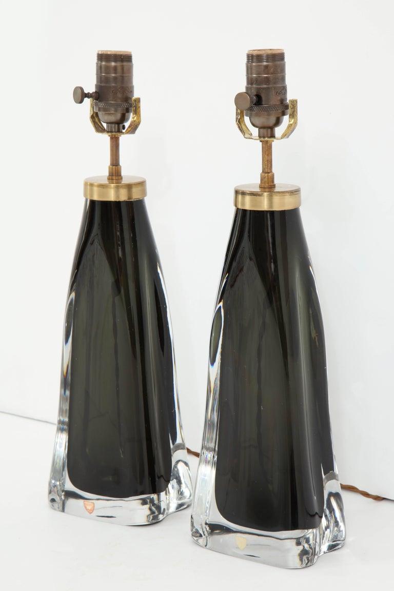 A pair of crystal lamps produced by Orrefors, Sweden, in a stunning black. The lamps have been recently re-wired for use in the U.S. and have brass fittings with cloth cords. The height is listed at the bottom of the harp.