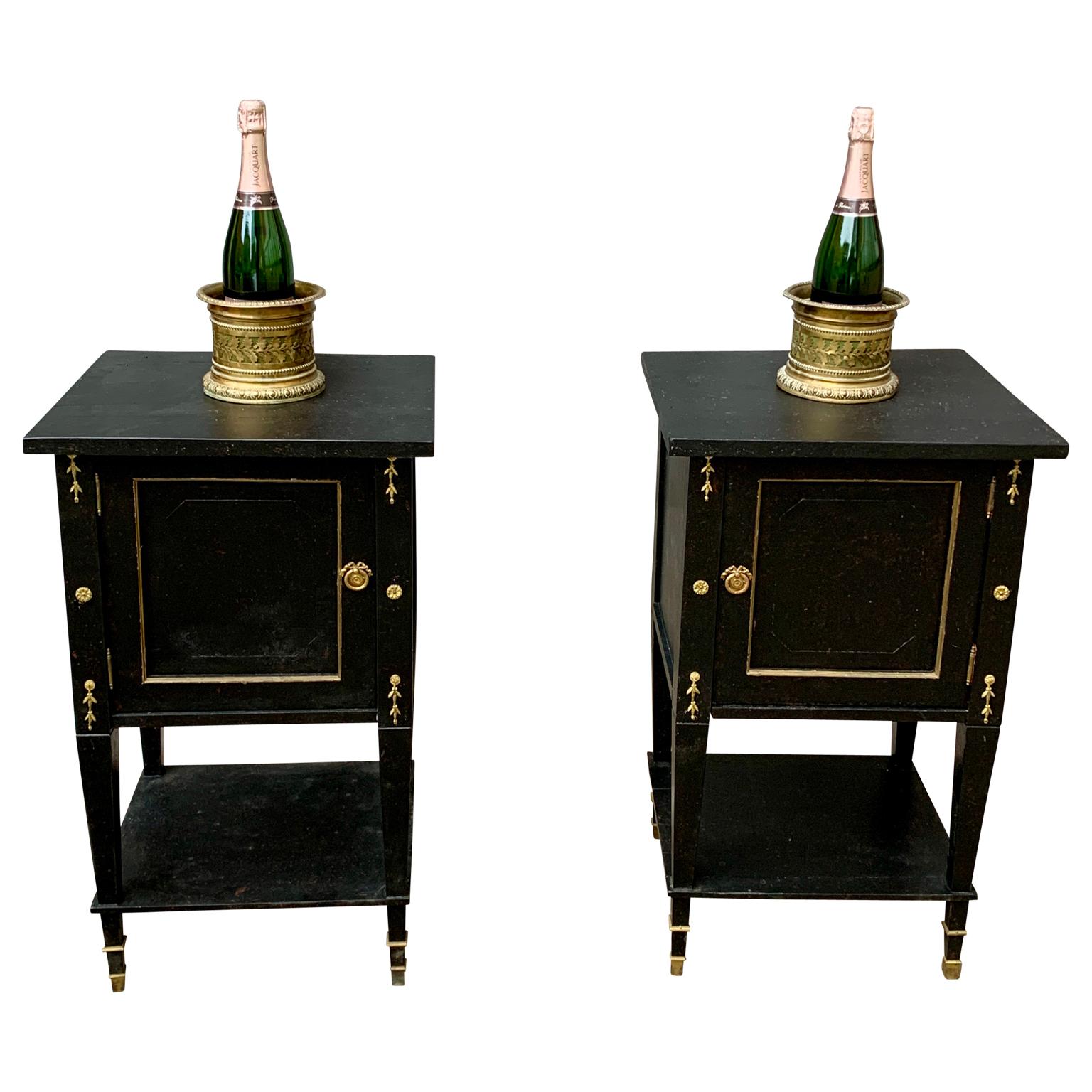 A pair of black painted early 20th Century Swedish Gustavian end tables or night tables with brass hardware and decorations. This pair of Scandinavian nightstands have doors that opens in opposite manner to be correctly put at each side of a bed. 