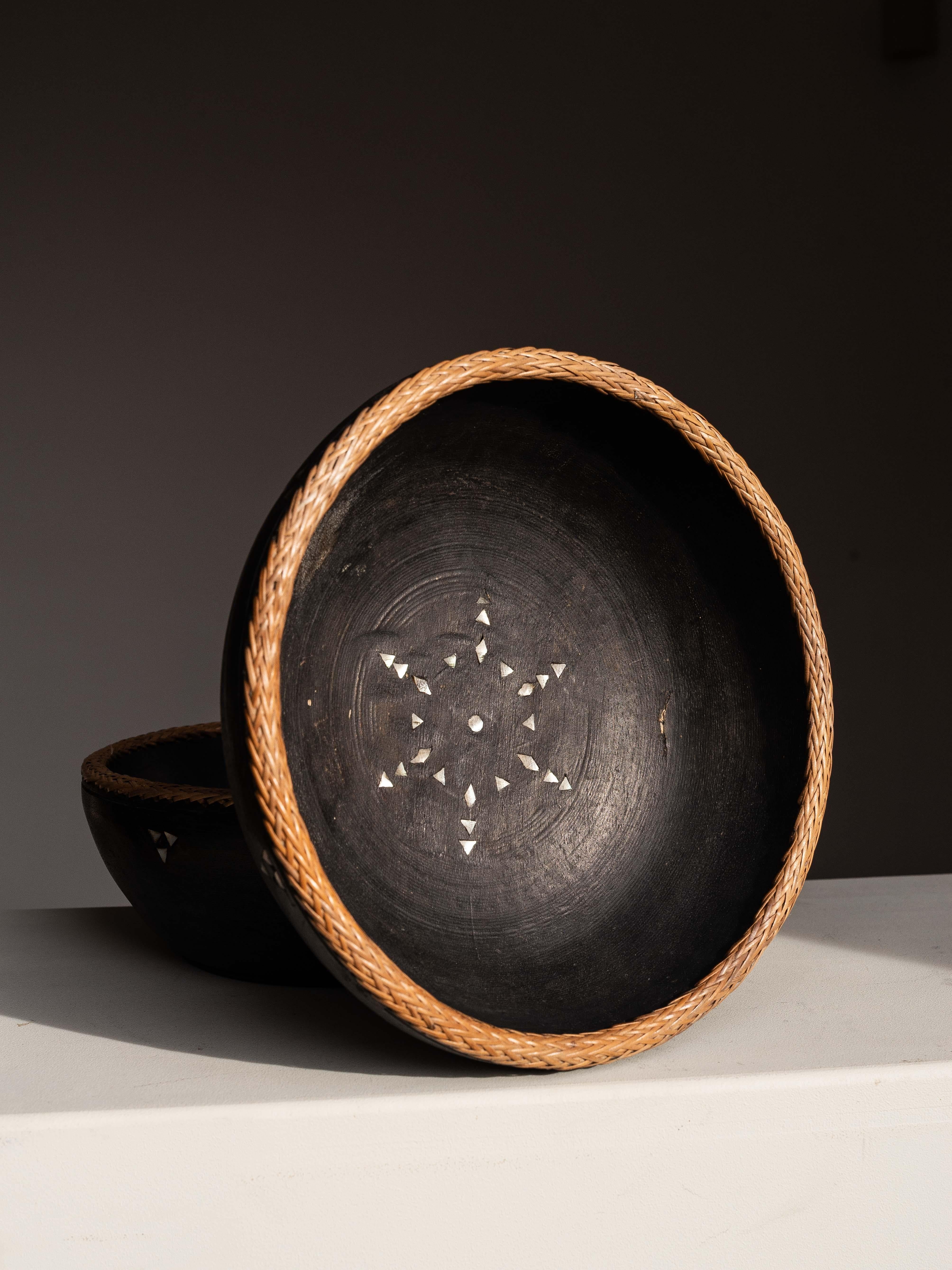 Pair of Blackened Wood Bowls with Rattan Rim and Mother-of-Pearl Inlay - 1980s

Set of 2 handcrafted wooden bowls or dishes from Southeast Asia, most likely the Philippines.

Each piece is carved from blackened wood and finished with a finely