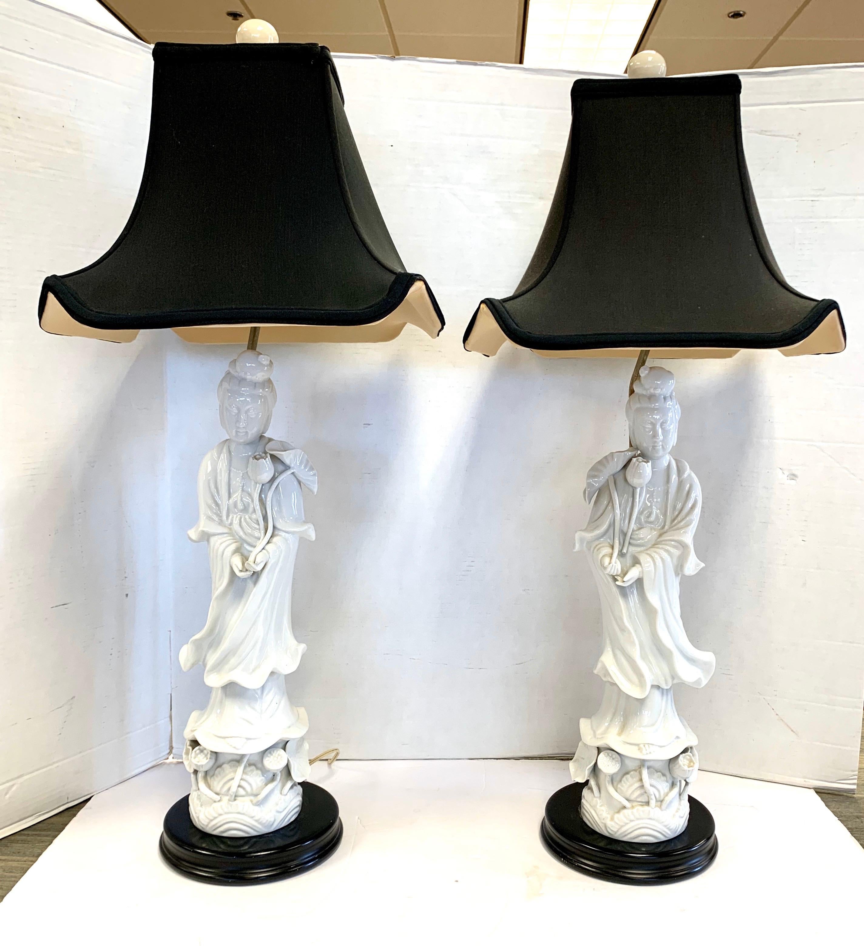 A pair of blanc de chine white figural porcelain table lamps of two geisha girls on black wood bases. Includes black silk pagoda shaped lampshade. 
Dimensions are below and the height of just the Blanc de Chine porcelain statue on each is 20 inches.