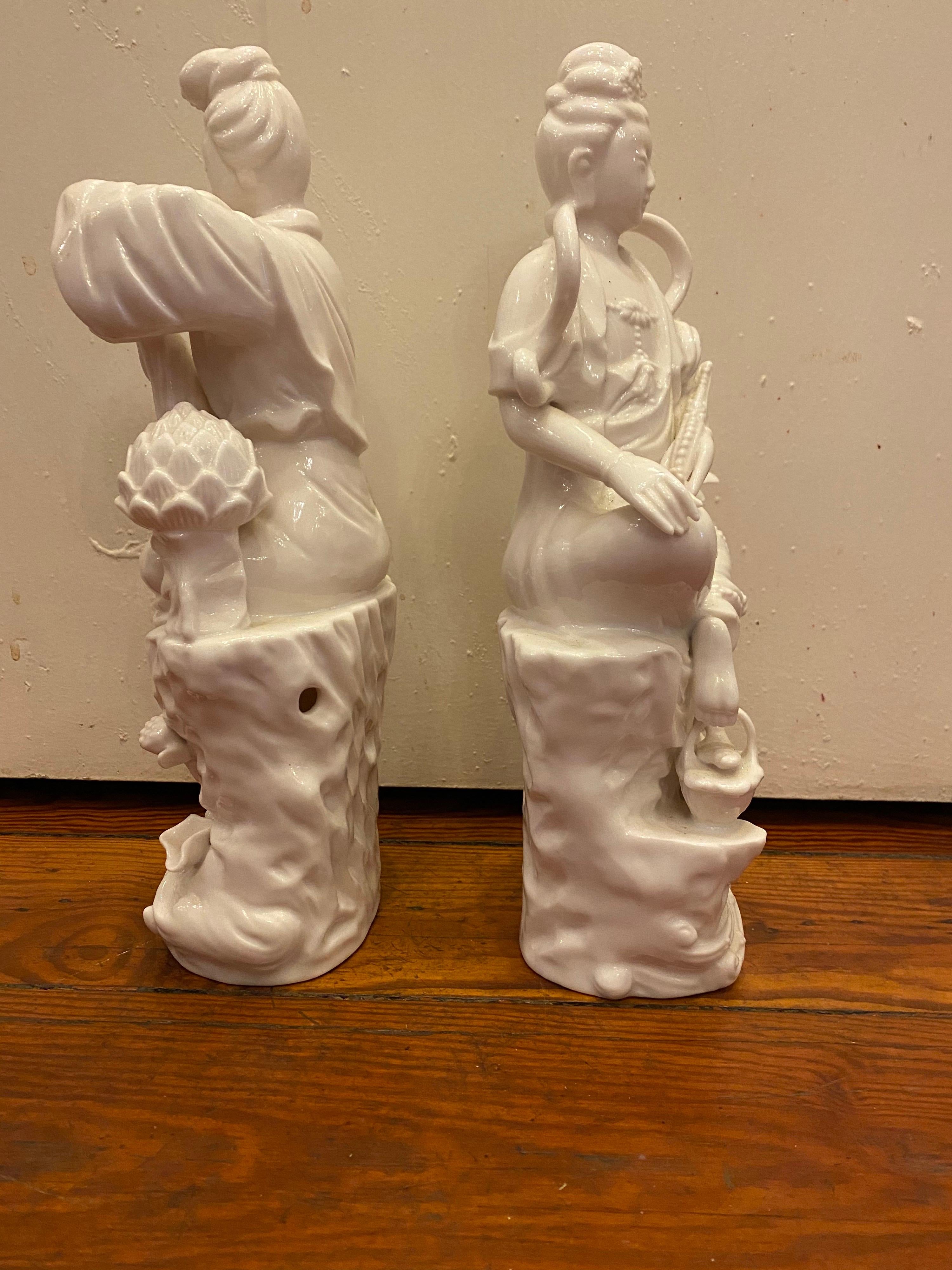 Pair of Blanc de Chine figures of ladies sitting on a tree stump with flowers.
