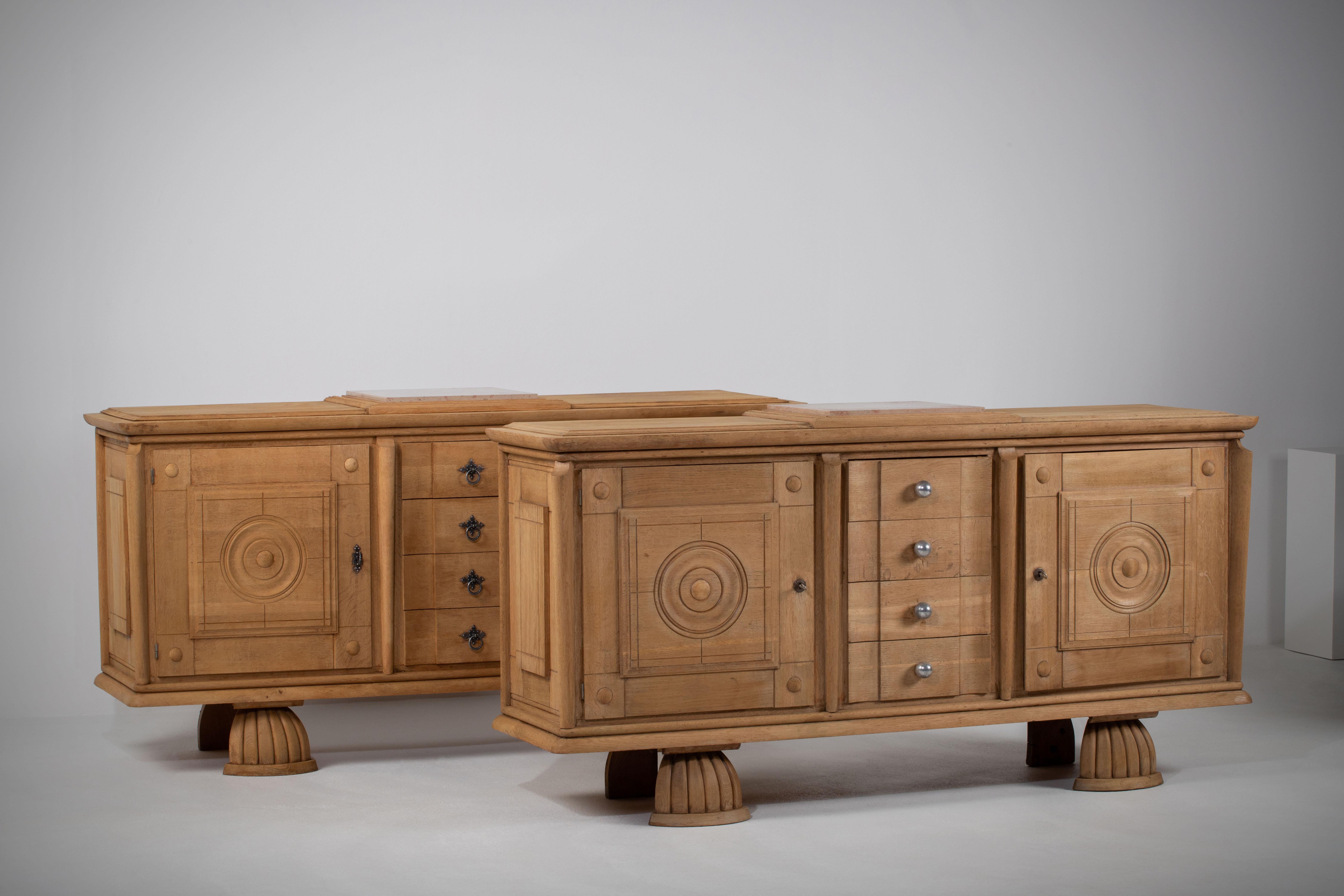 Pair of credenzas, solid oak, France, 1940s.
Large Art Deco brutalist sideboard.
The credenza consists of two storage facilities with the center drawers.
The refined wooden structures on the doors create a striking combination with the otherwise