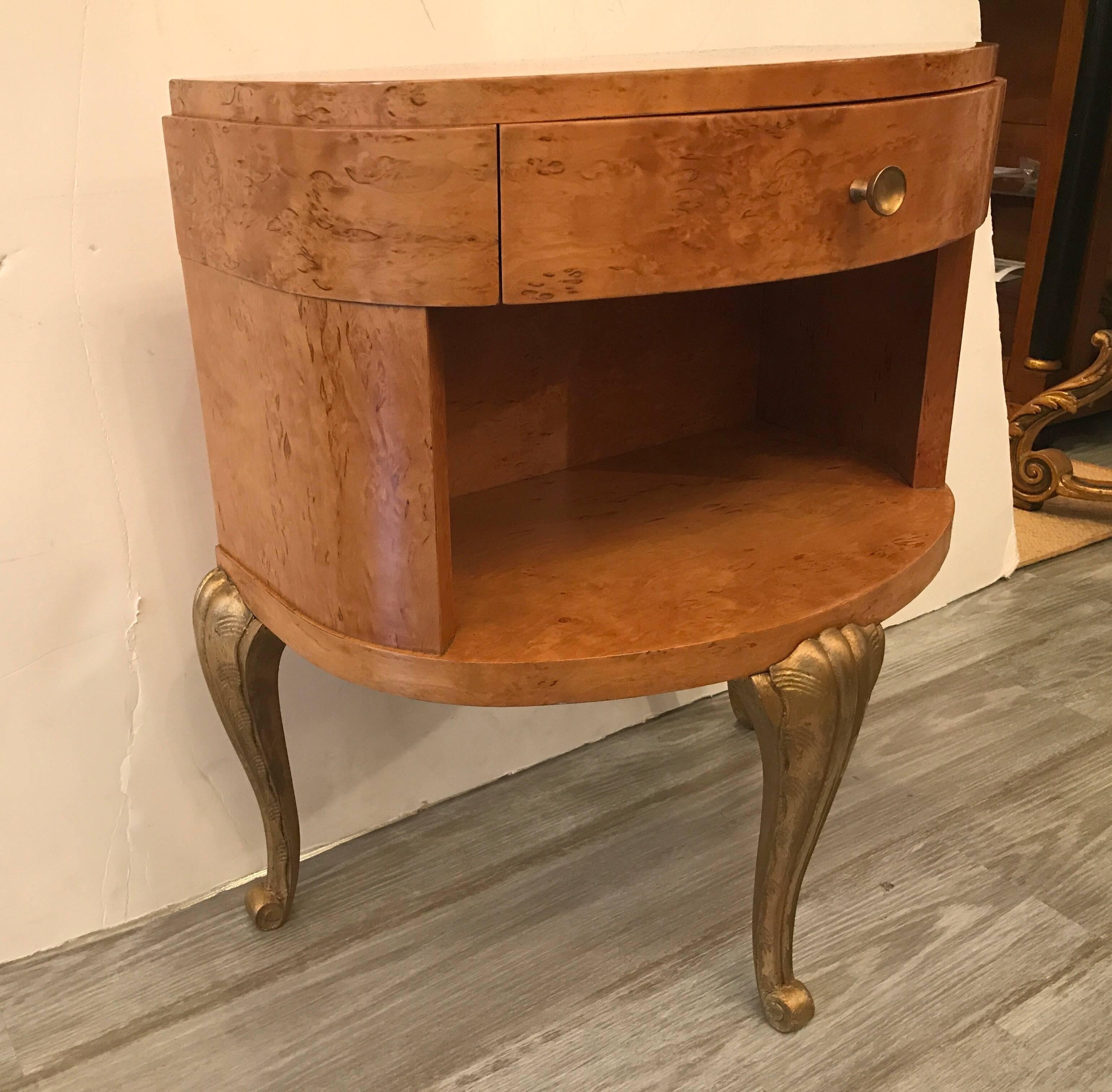 A chic pair of blond wood nightstands. The carved legs with gilt finish support the demilune shape tops. One central drawer over and open display section. Very nice finish on both.