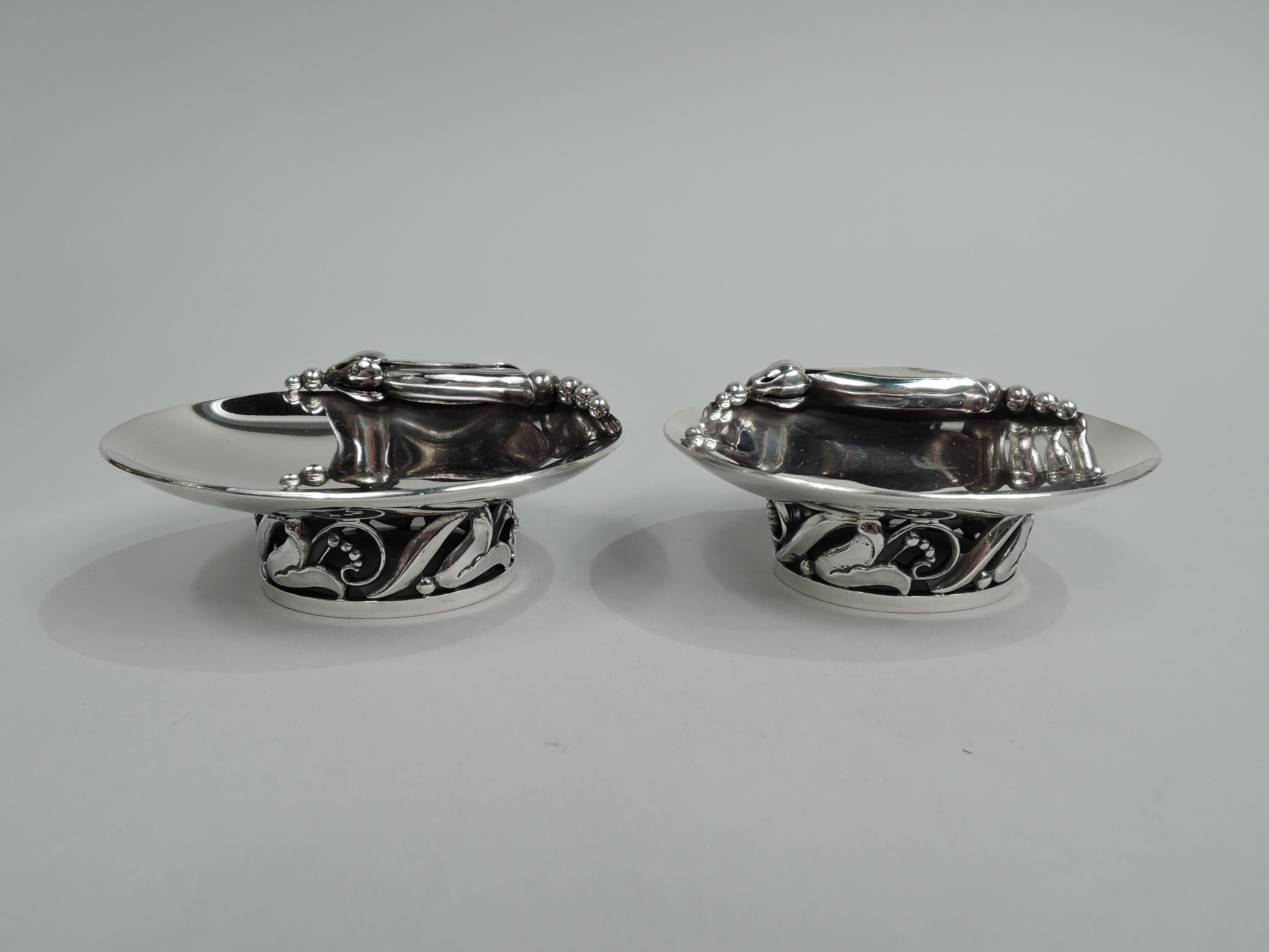 Pair of Mid-Century Modern sterling silver open salts. Made by Alphonse La Paglia (d. 1953) for Georg Jensen USA, Inc. in New York. Each: Shallow and curved oval bowl applied with Blossom-inspired seed-spilling pod. Open foot with stylized floral