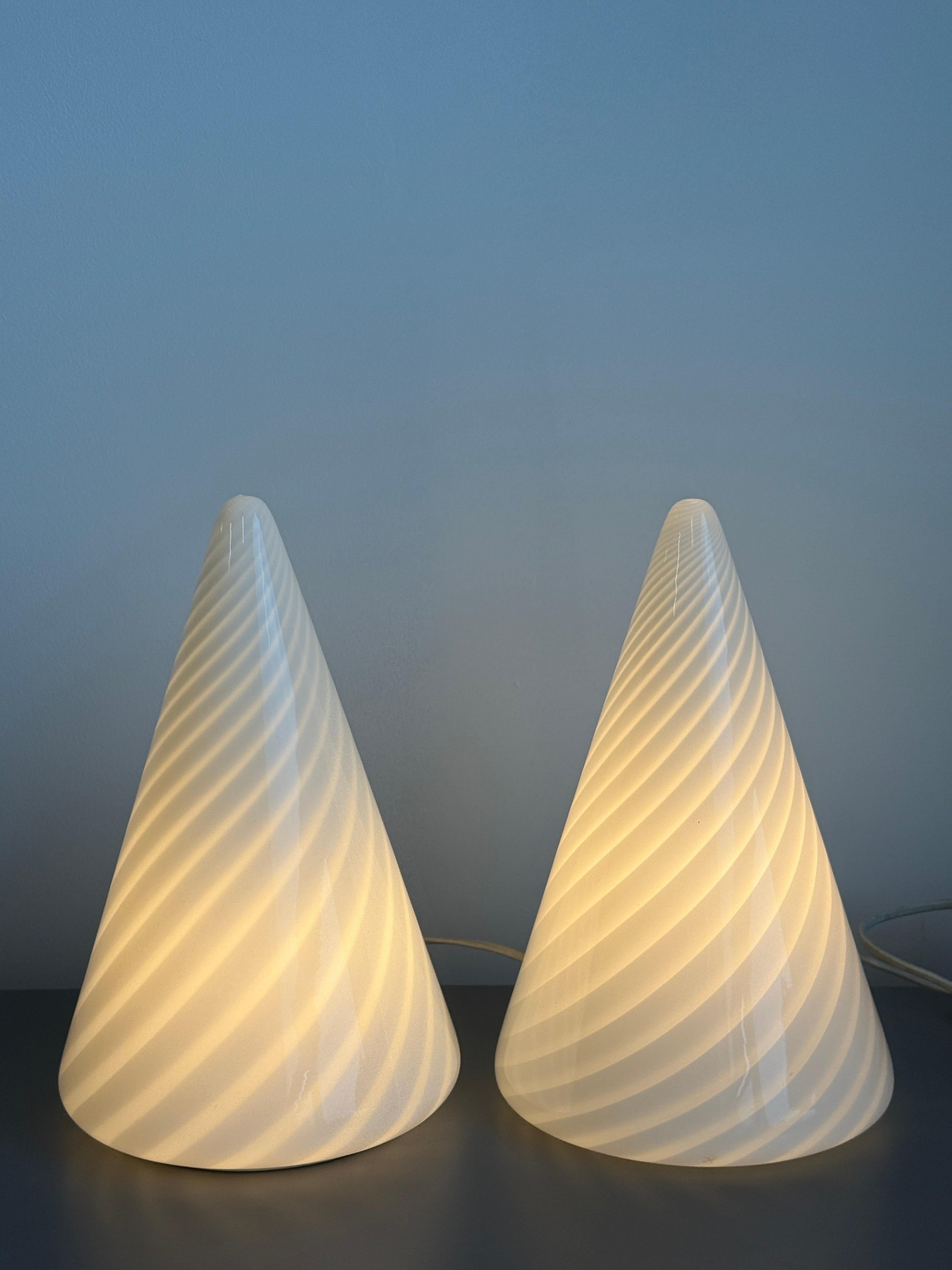 Paire de lampes de table coniques en verre soufflé de Murano (vers les années 1960) dans le style de Paulo Venini. Modernistes et élégantes, ces lampes en verre de Murano constituent une source d'éclairage à la fois utilitaire et décorative. L'effet
