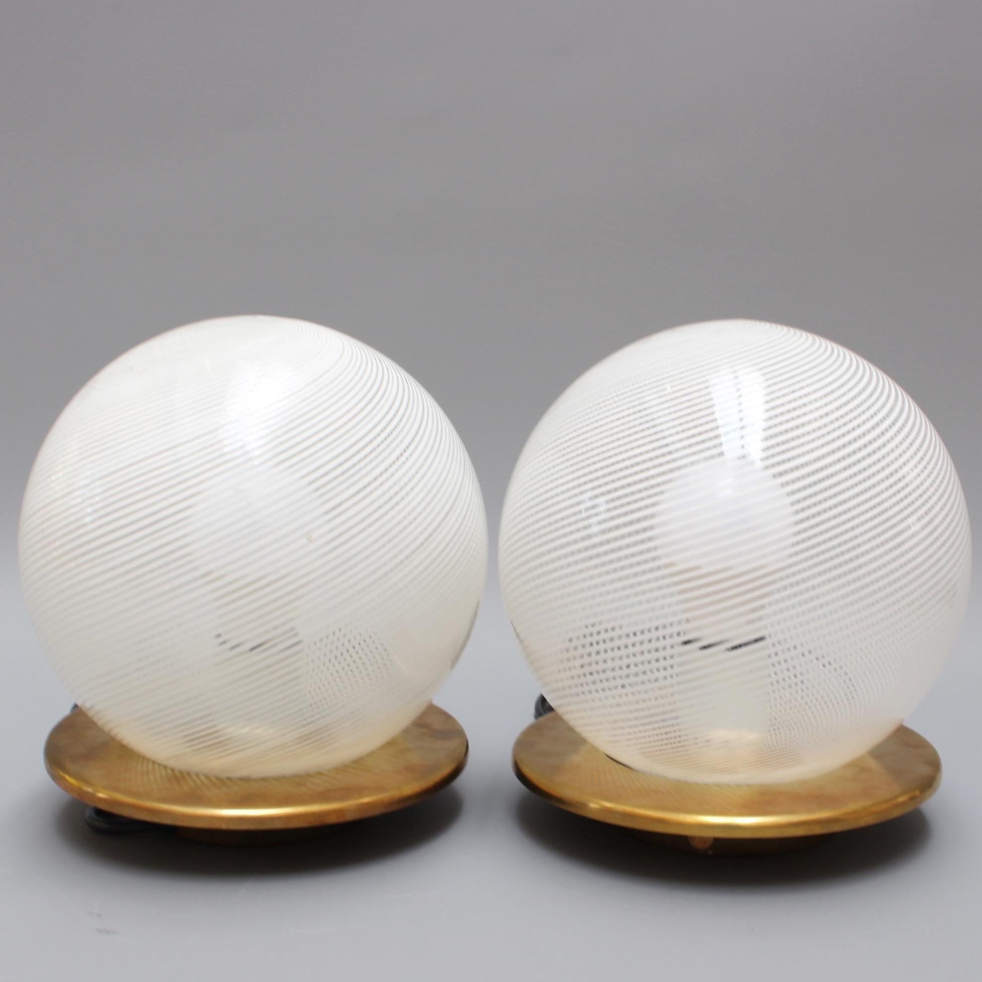 Pair of blown Murano glass globe table lamps (circa 1950s) in the style of Paulo Venini. Modernist and elegant, these blown Murano glass globe lamps provide a source of lighting which is both functional and decorative. The stripe effect was ahead of