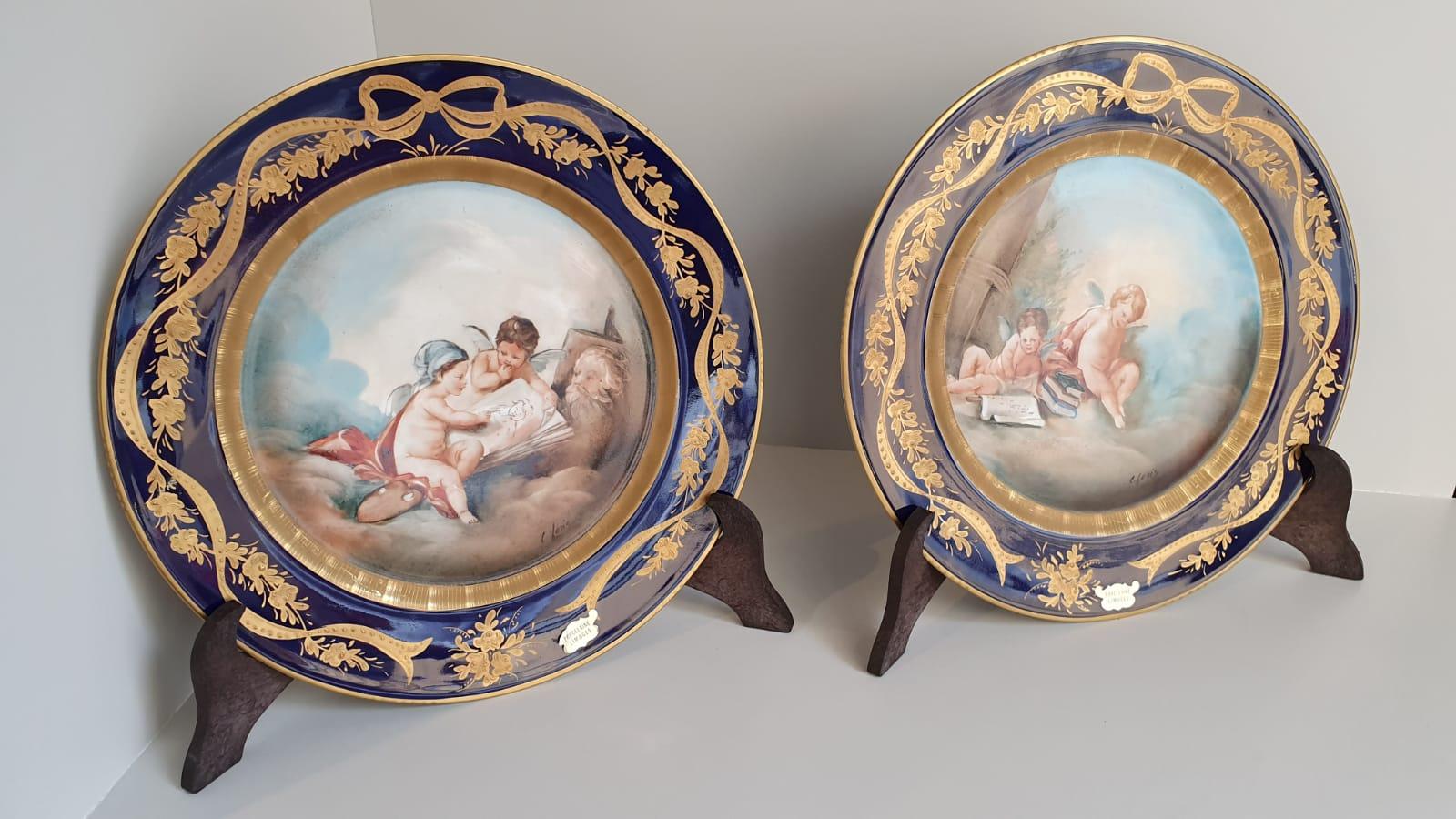 Pair of porcelain plates made in Limoges in France in 1980 and subsequently hand painted by an Italian artist.
The frame of the plate is decorated with floral motifs and a large bow in gold with relief dots, which Stand out on a cobalt blue