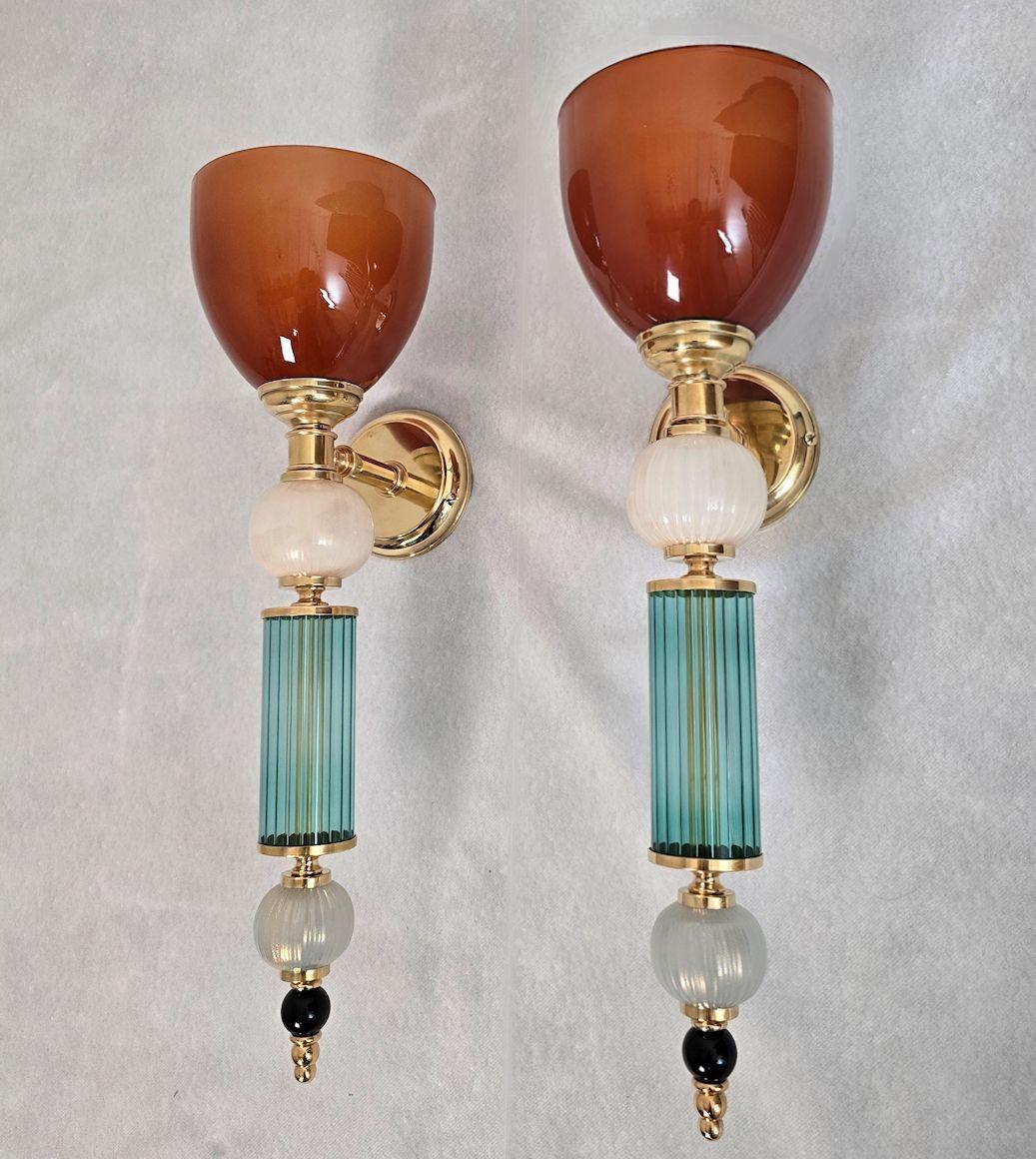 Coppia di appliques in vetro di Murano della metà del secolo scorso, Italia, anni '1990 circa.
La coppia di appliques italiane è realizzata in vetro blu petrolio e terracotta e con elementi in vetro di Murano.
I supporti sono in ottone lucido.
Il