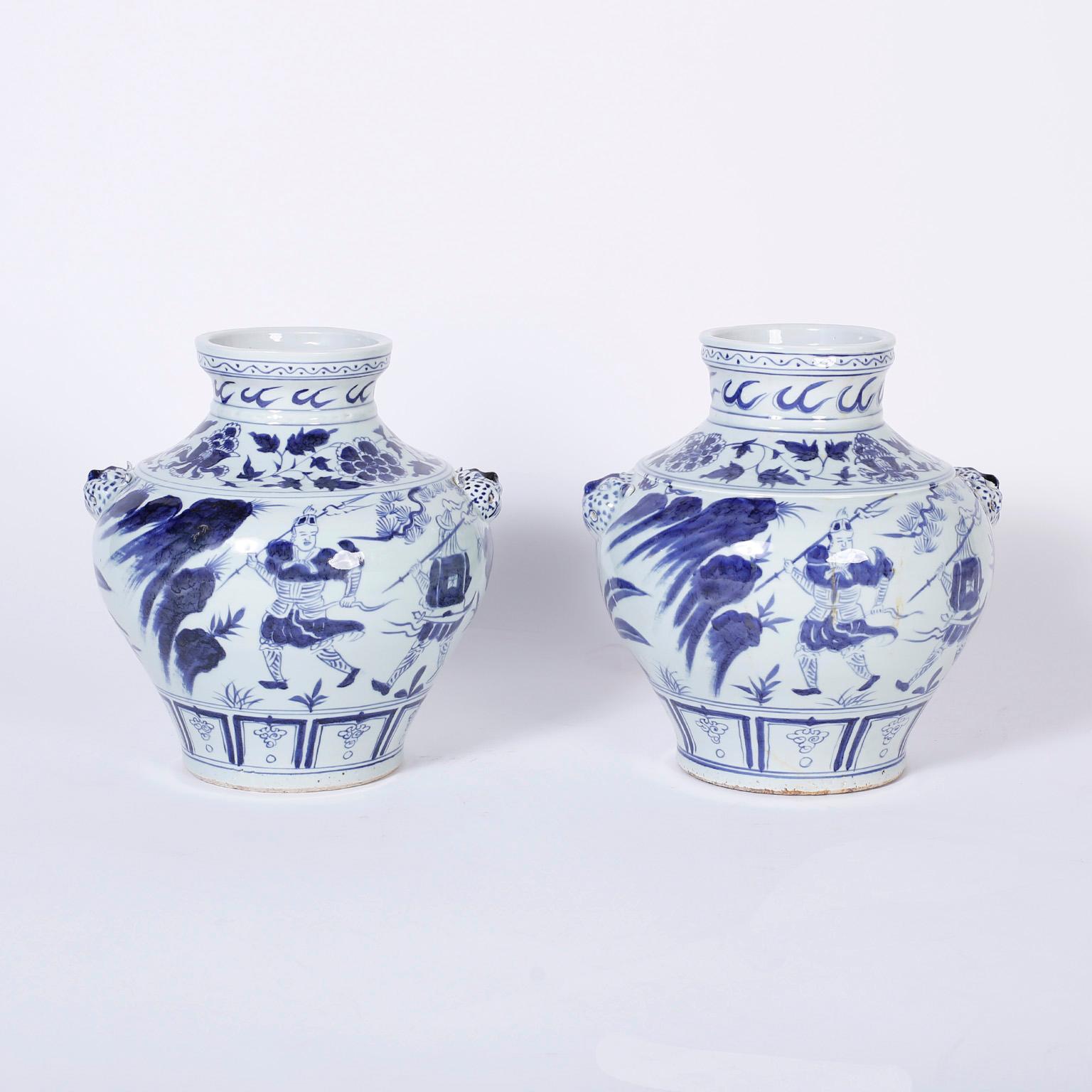 Intriguing pair of Chinese export style blue and white urns decorated with figures and flowers and having the unusual leopard head handles.