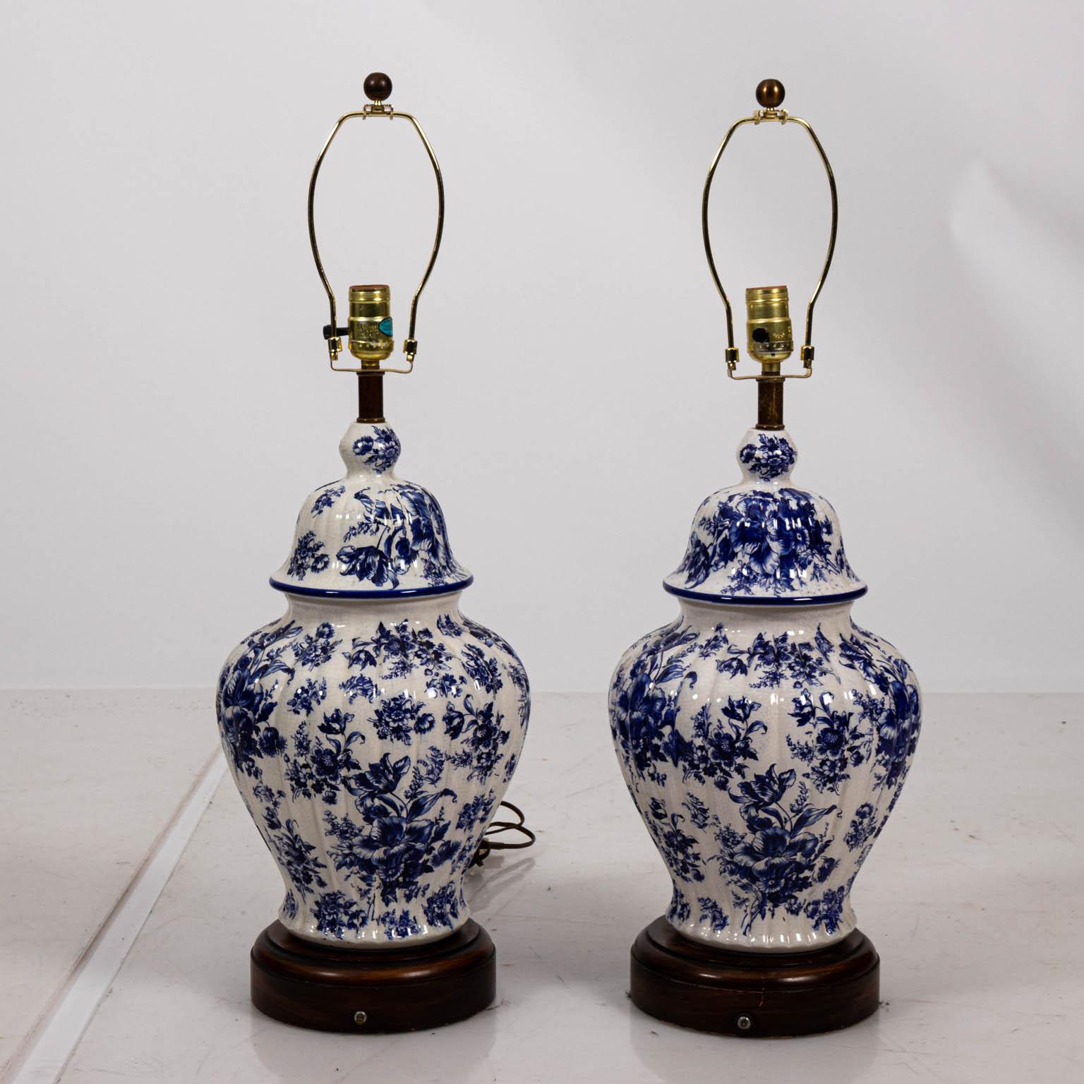 Paar blau-weiße chinesische Tempellampen mit floralen Details auf Holzsockeln. Bitte beachten Sie die altersbedingten Abnutzungserscheinungen wie Absplitterungen und Lackschäden. Die Lampenschirme sind nicht enthalten.